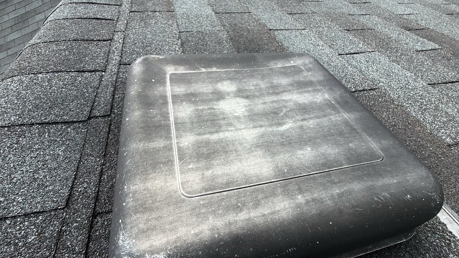 Hail impact dents and scuffs on a metal roof vent cap