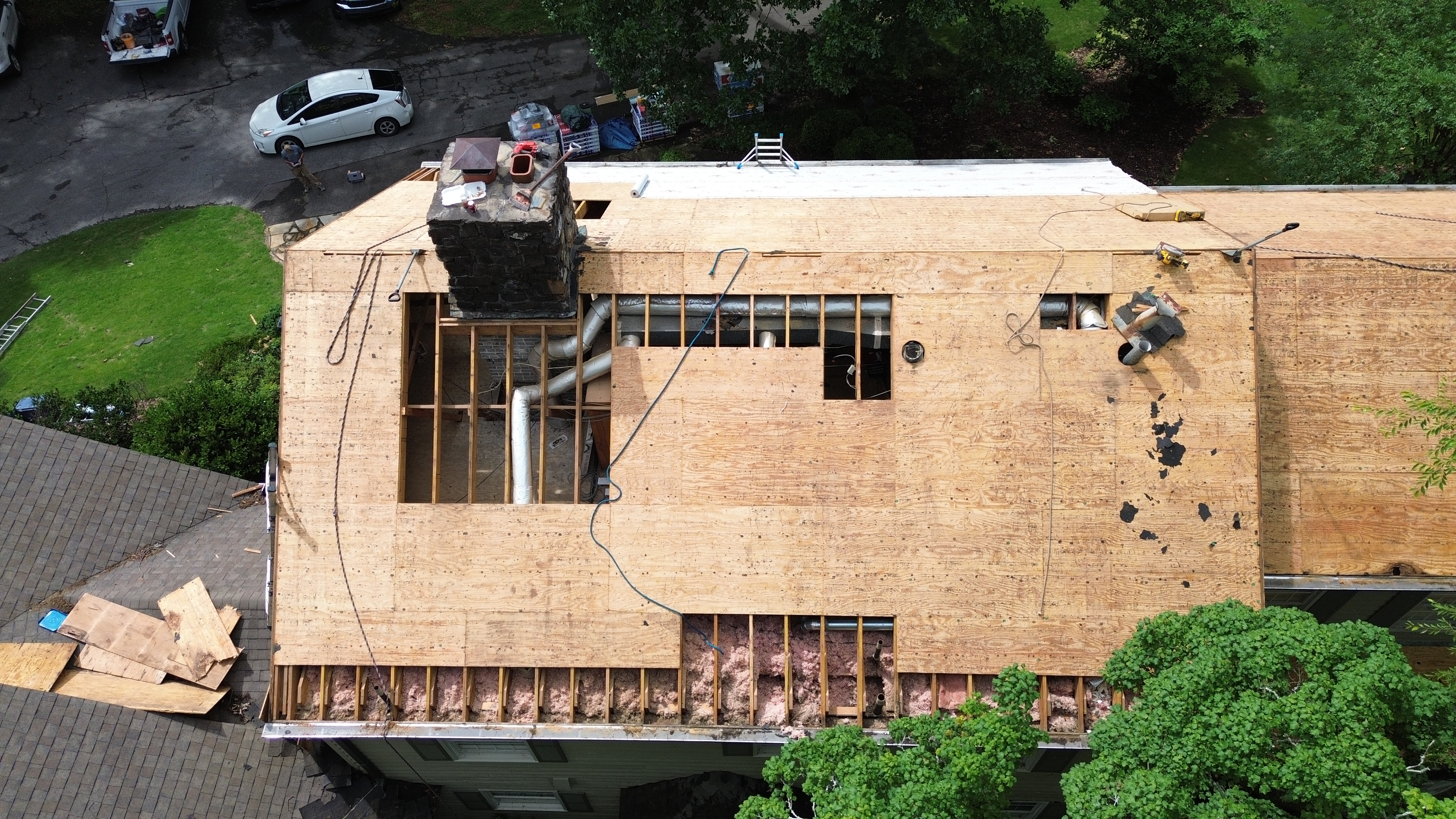 Exposed rafters and pink insulation are visible before new sheathing is secured in Mountain Brook.