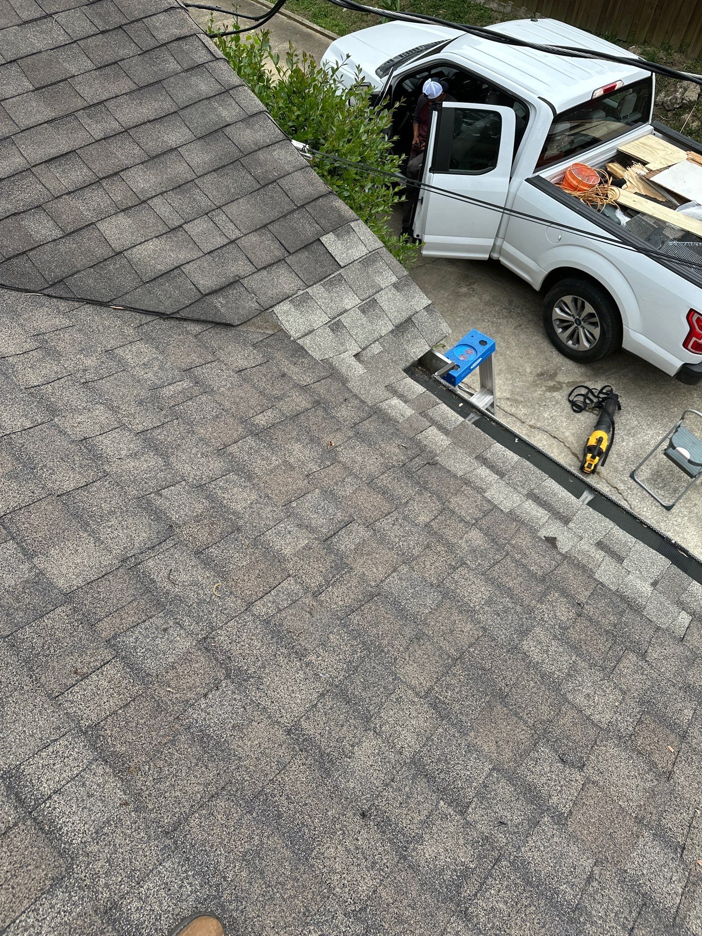 A completed shingle roofing repair with new grey shingles is visible from above on an Irondale home.