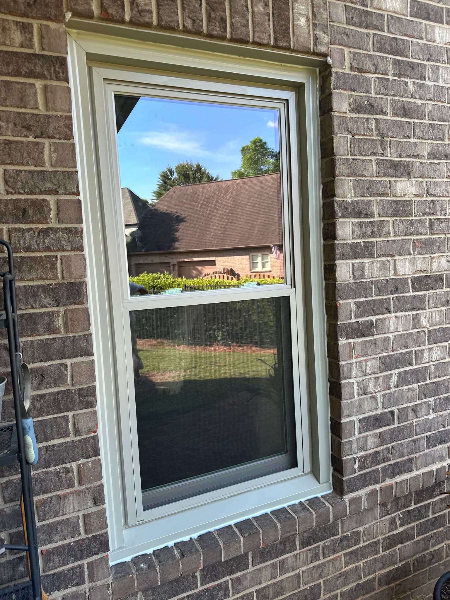 A newly installed double-hung window with a tan frame on a brick home in the Bluff Park neighborhood of Hoover.