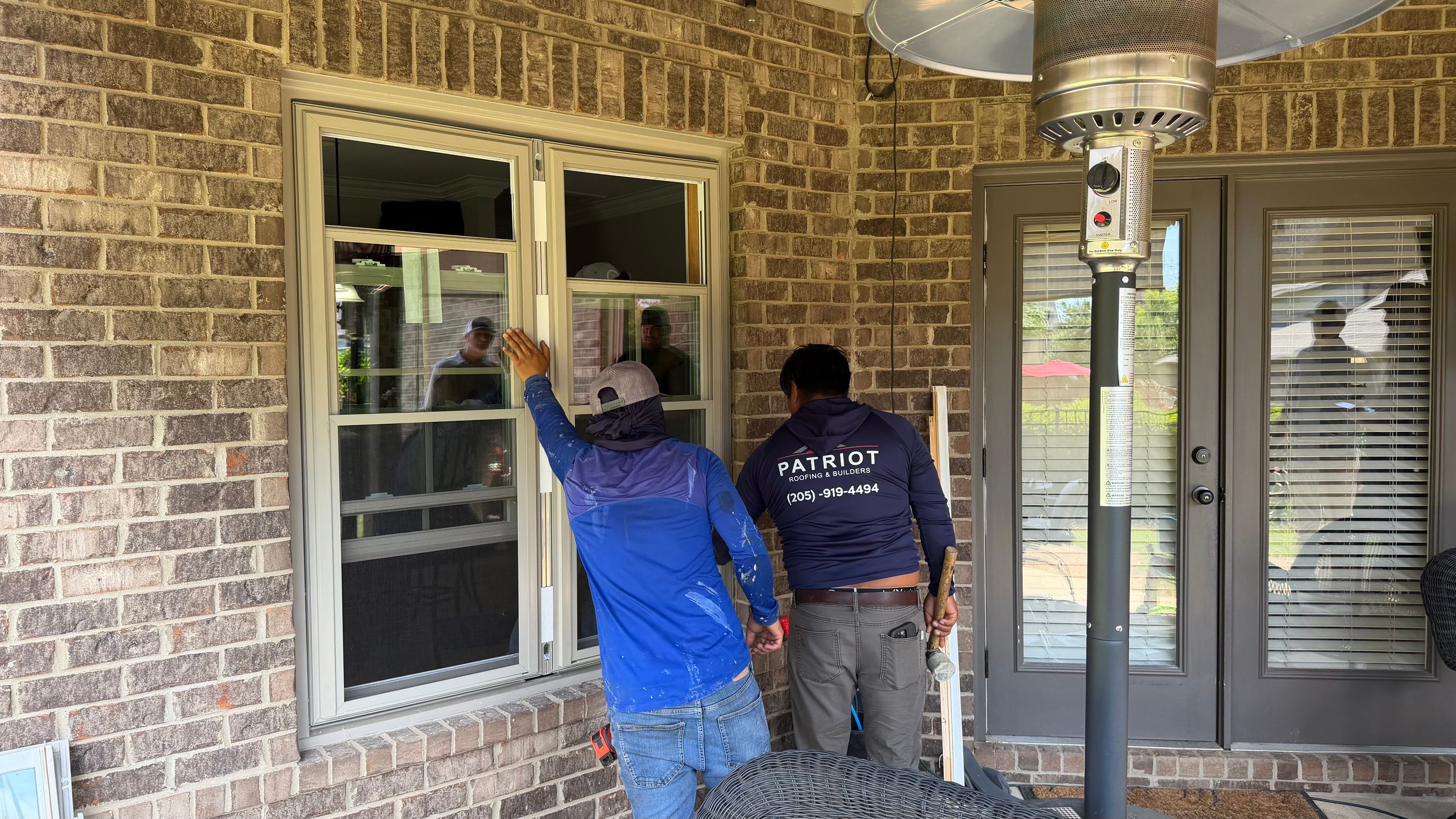 A new white-framed window is being installed into a brick wall at a residence in the Bluff Park neighborhood.