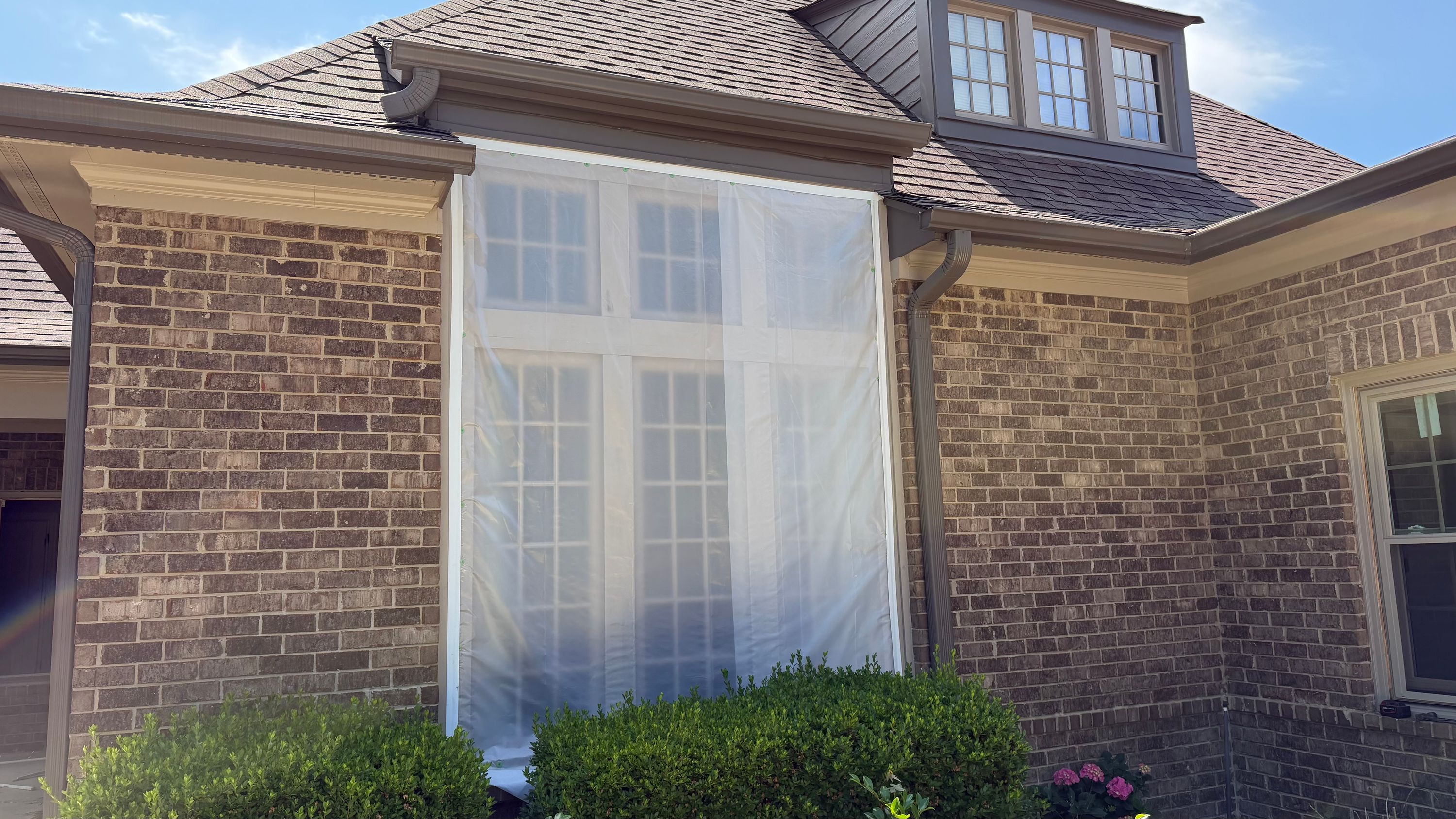 Plastic sheeting covers a large window during a replacement project at a brick home in Bluff Park, Hoover.
