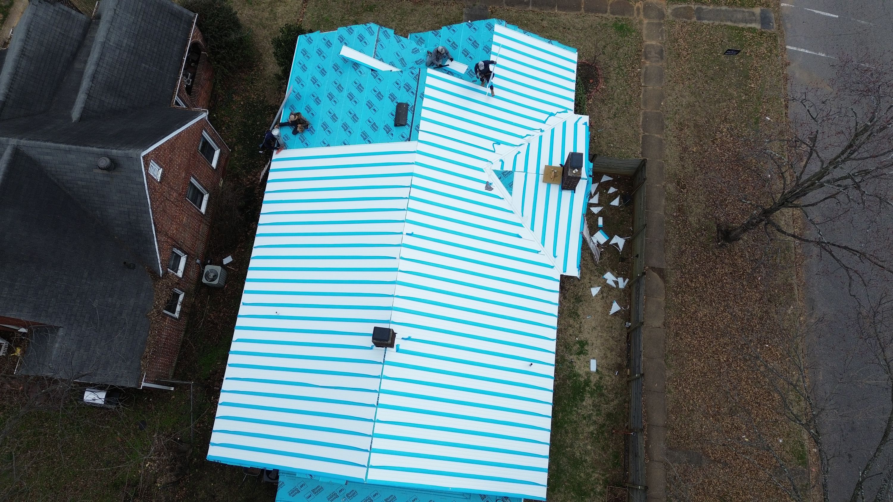 Aerial view of a roof replacement project in Glen Iris, Birmingham, showing protective blue and white underlayment.