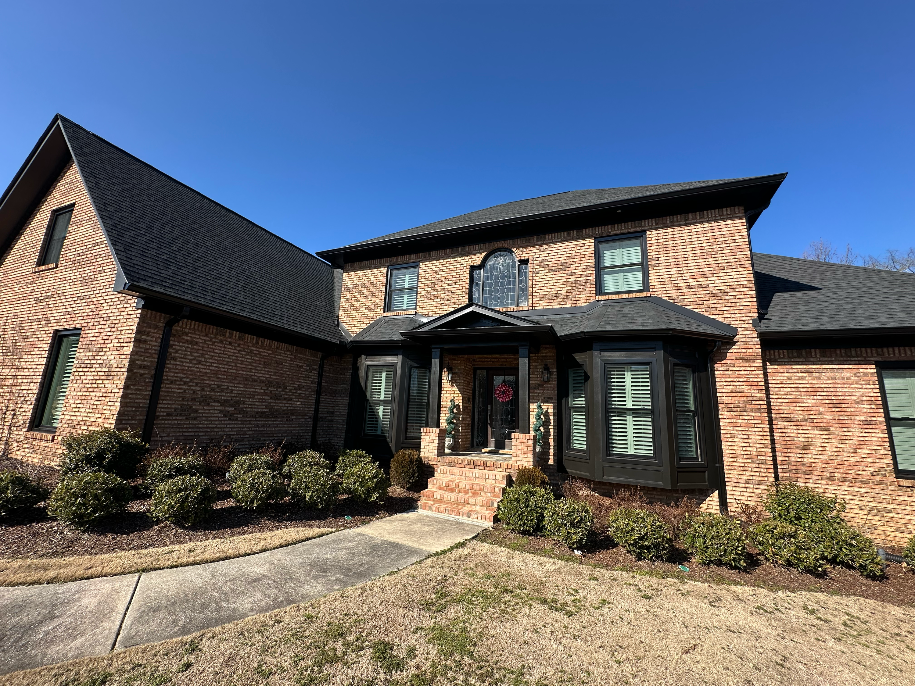 Exterior of a large brick home in Hoover, Alabama showcasing newly installed black framed windows.