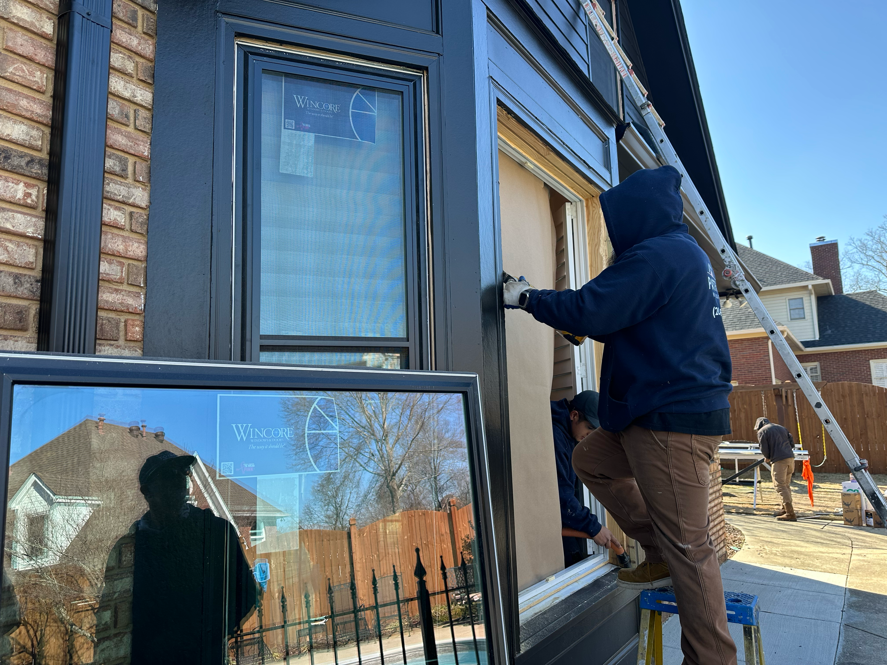 Expert window installation in Hoover showing a worker securing a new black Wincore window frame.