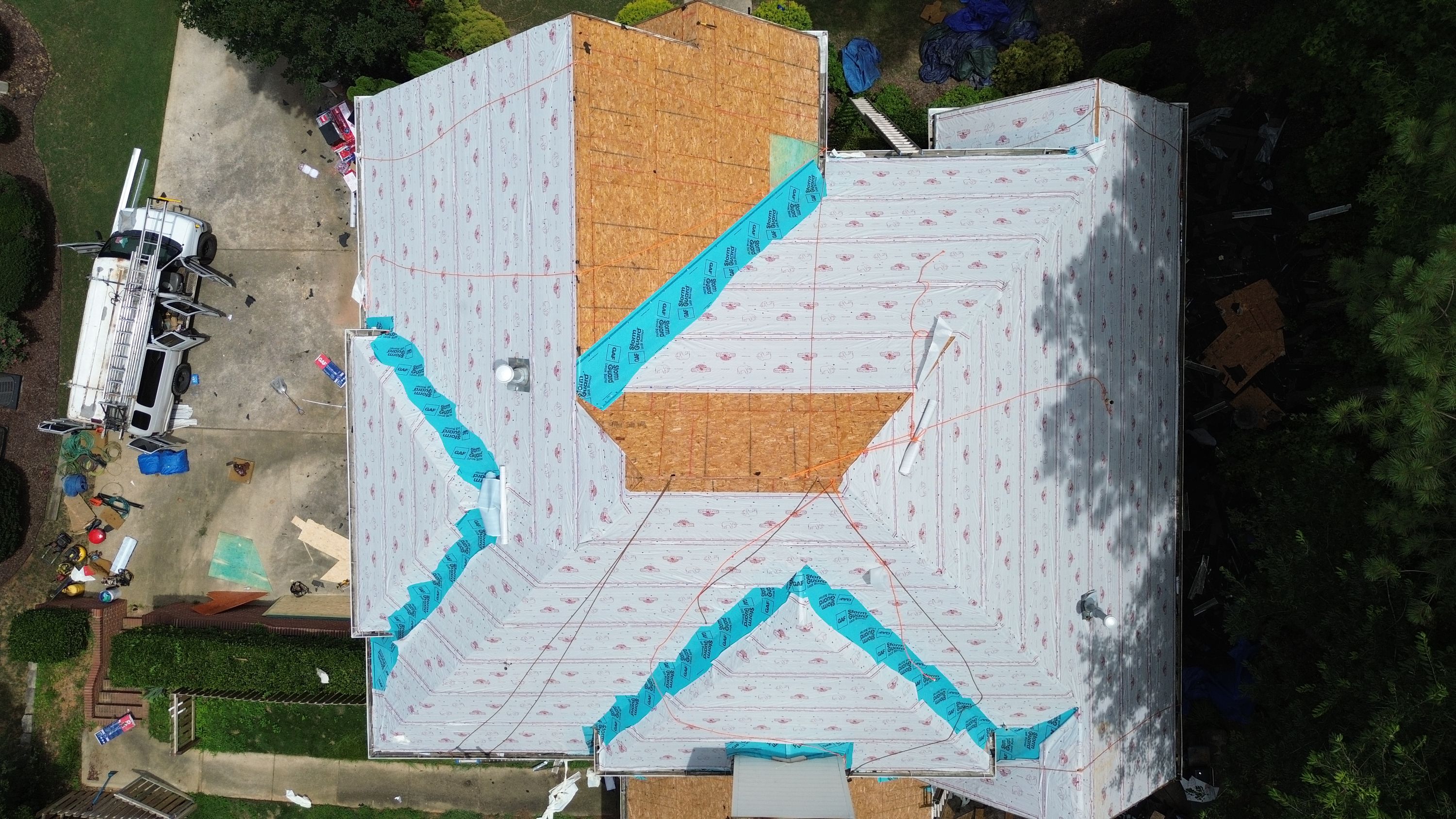 Aerial view of a roof replacement in Hoover showing synthetic underlayment and blue valley leak barrier.