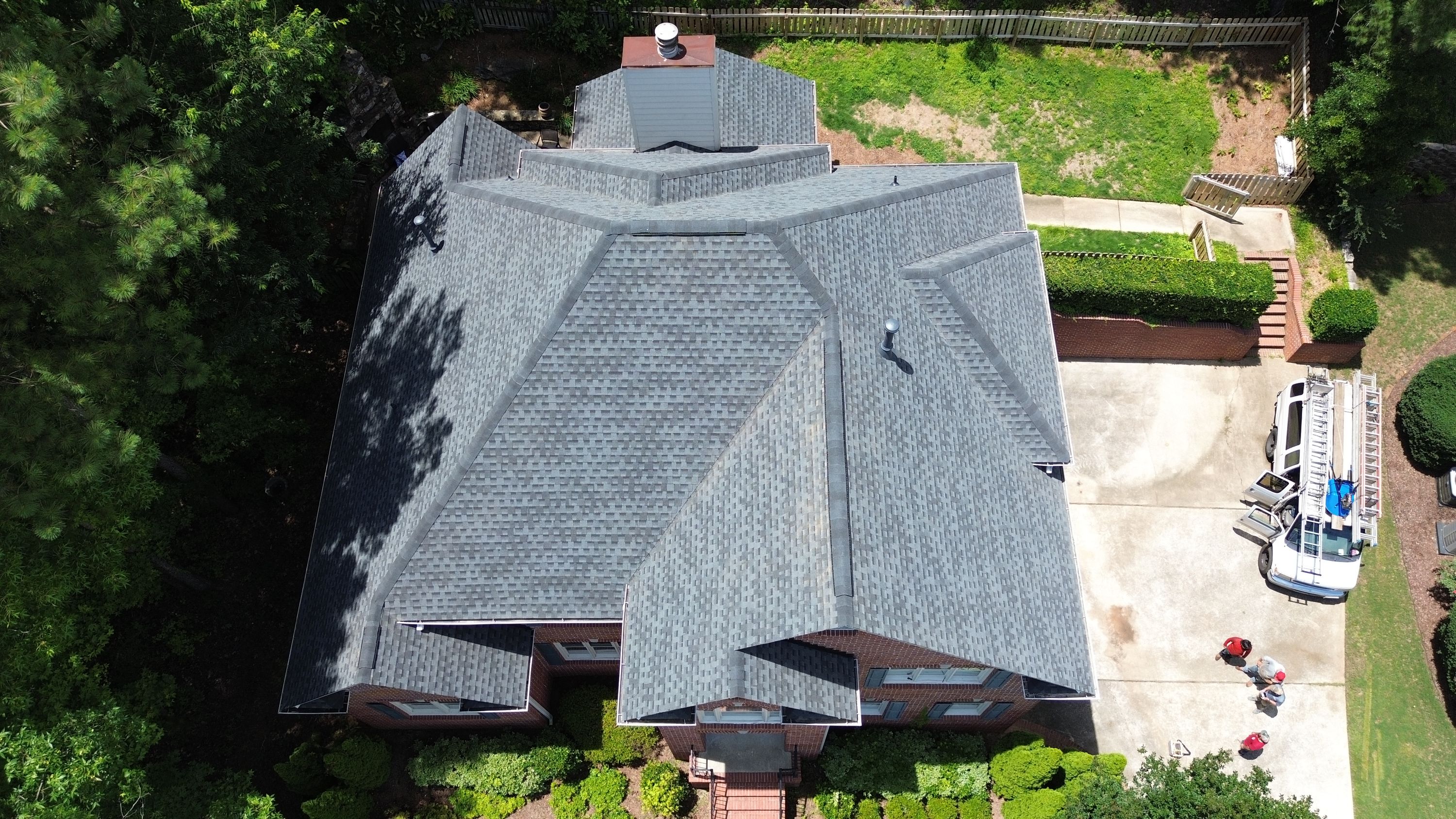 Aerial view of a completed dark gray shingle roof replacement on a brick home in Hoover.