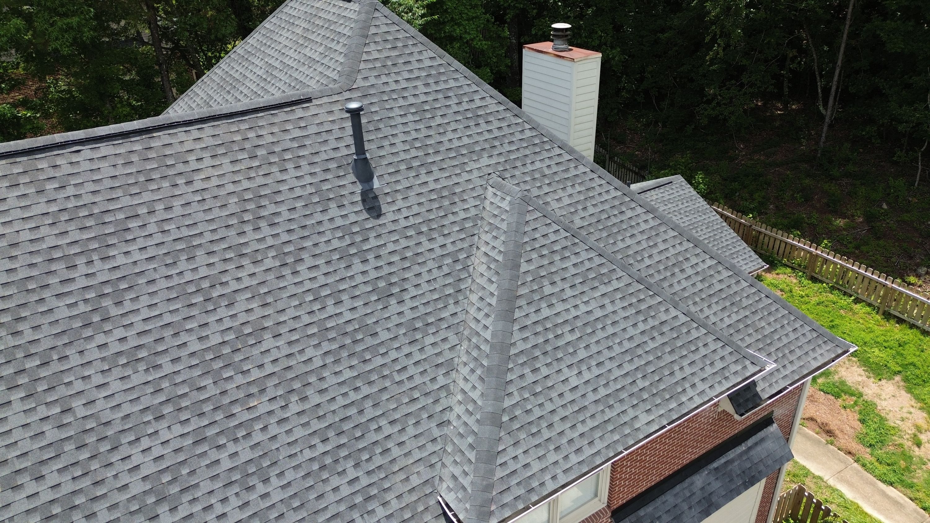 Aerial view of a completed grey shingle roof replacement on a brick home in Hoover.