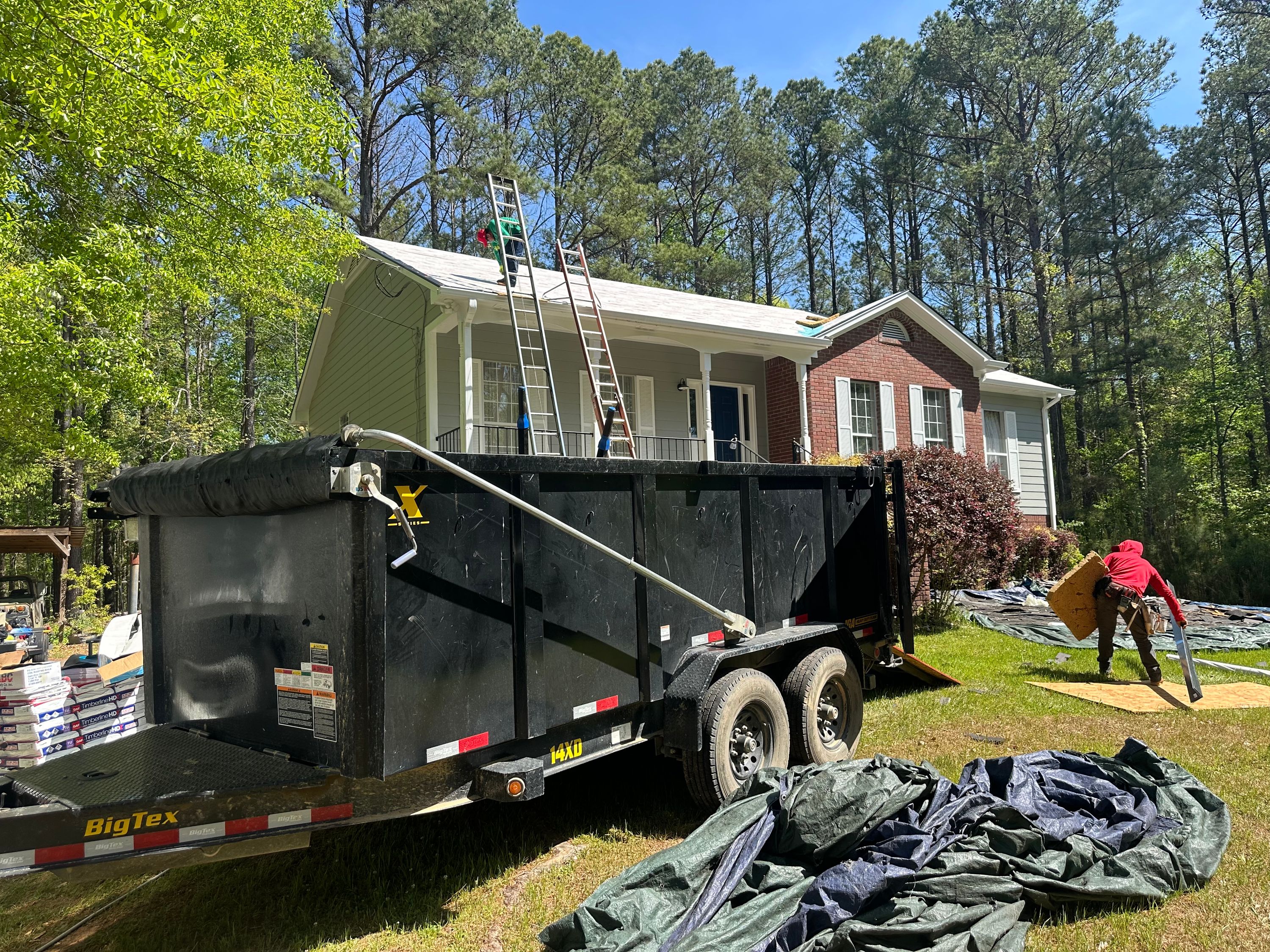 Roof replacement on a home in Chelsea featuring a dumpster for debris removal and ladders against the house.