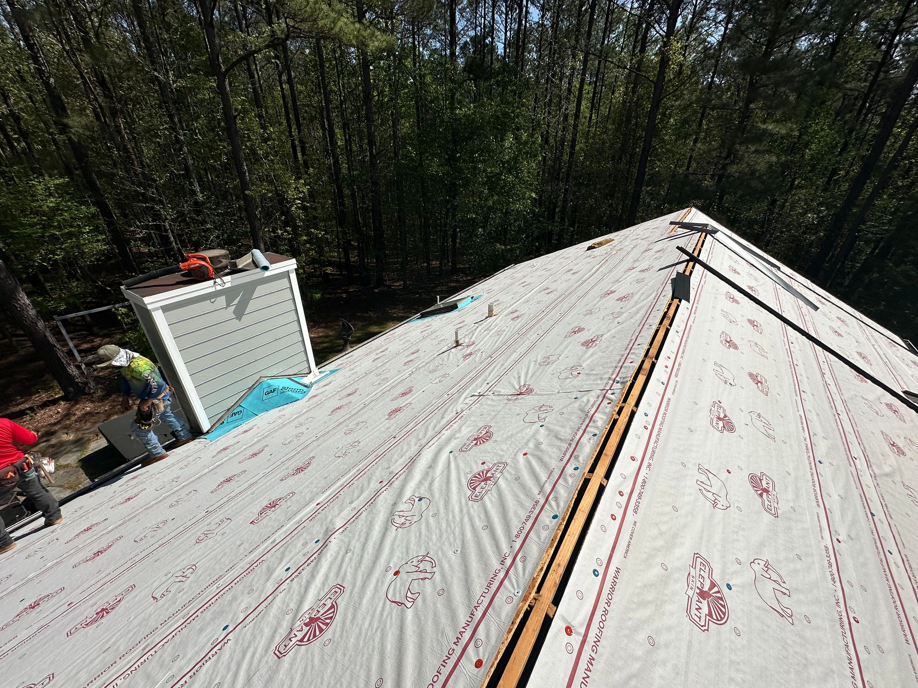Roof replacement in progress in Chelsea, featuring newly installed synthetic underlayment on the roof deck.