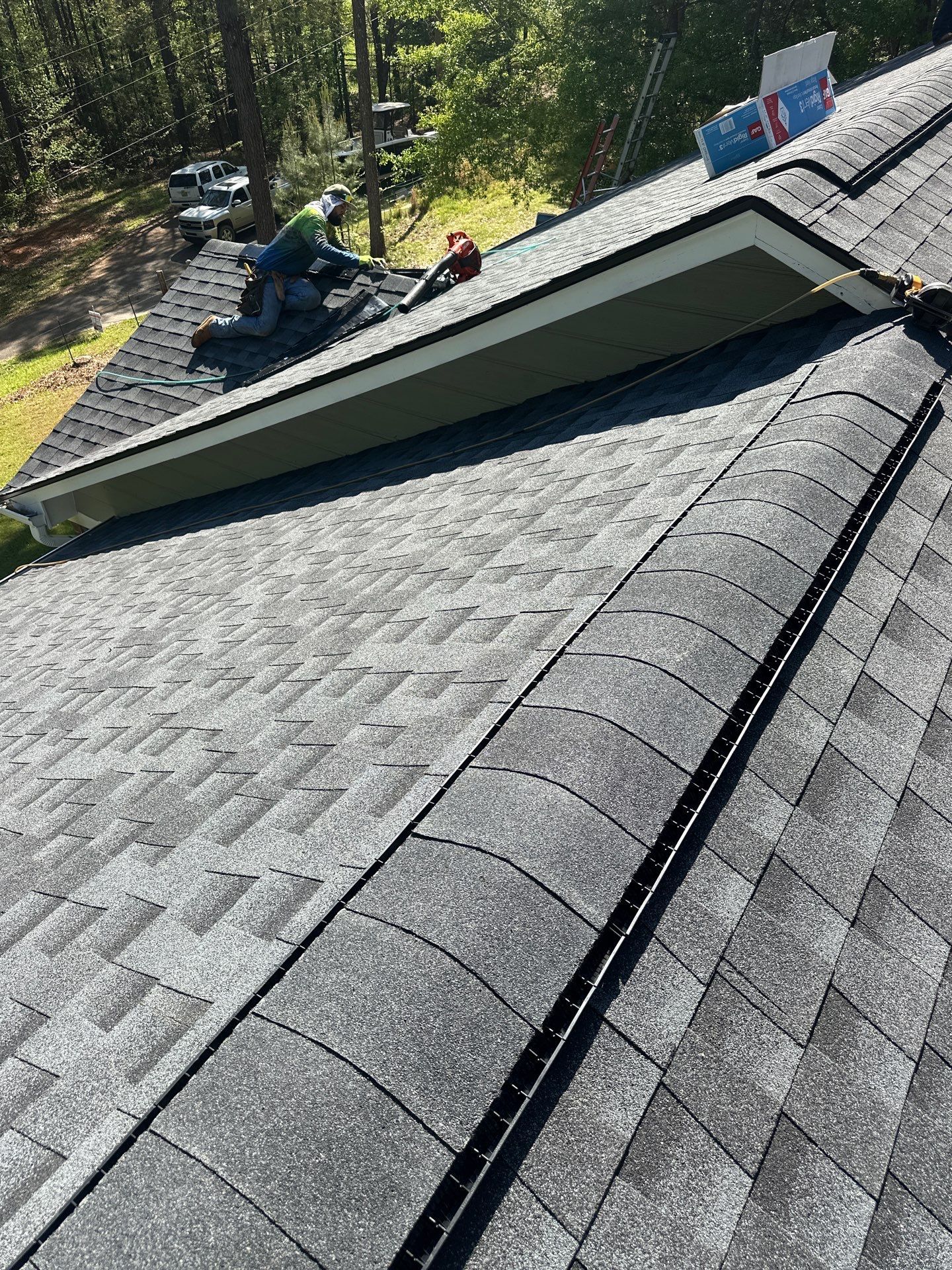 A roofer installs asphalt shingles during a roof replacement on a home in Chelsea.