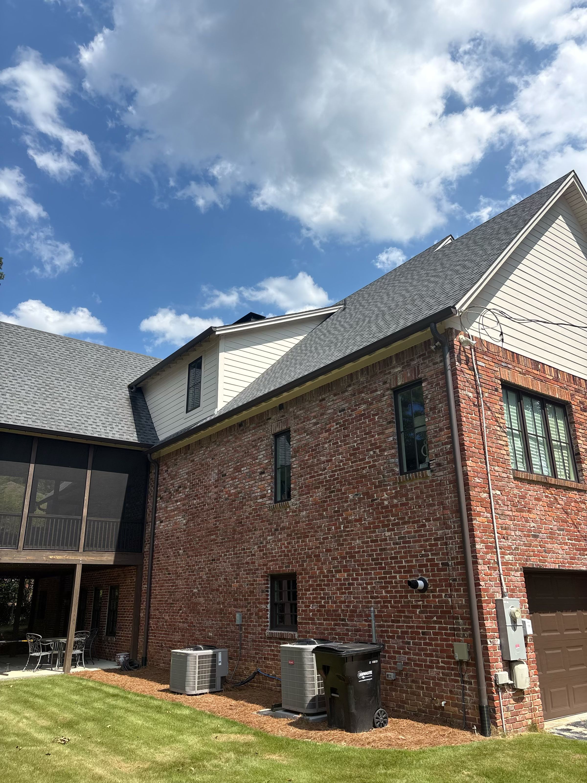 Dark gutters fitted with gutter guards line the roof edge above the brick exterior of this Mountain Brook residence.