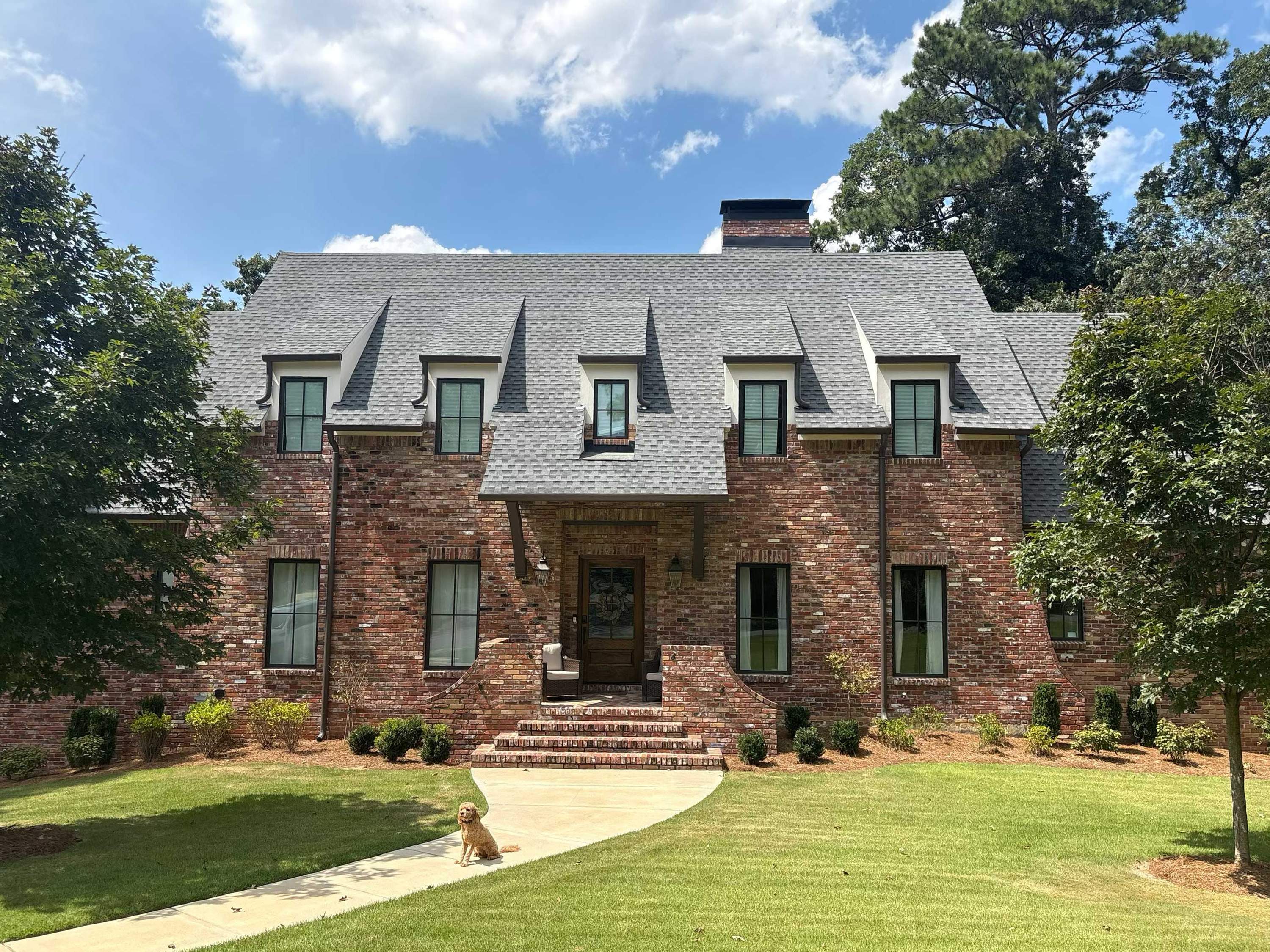 Protective gutter guards are installed on the dormer gutters above a brick front entrance.