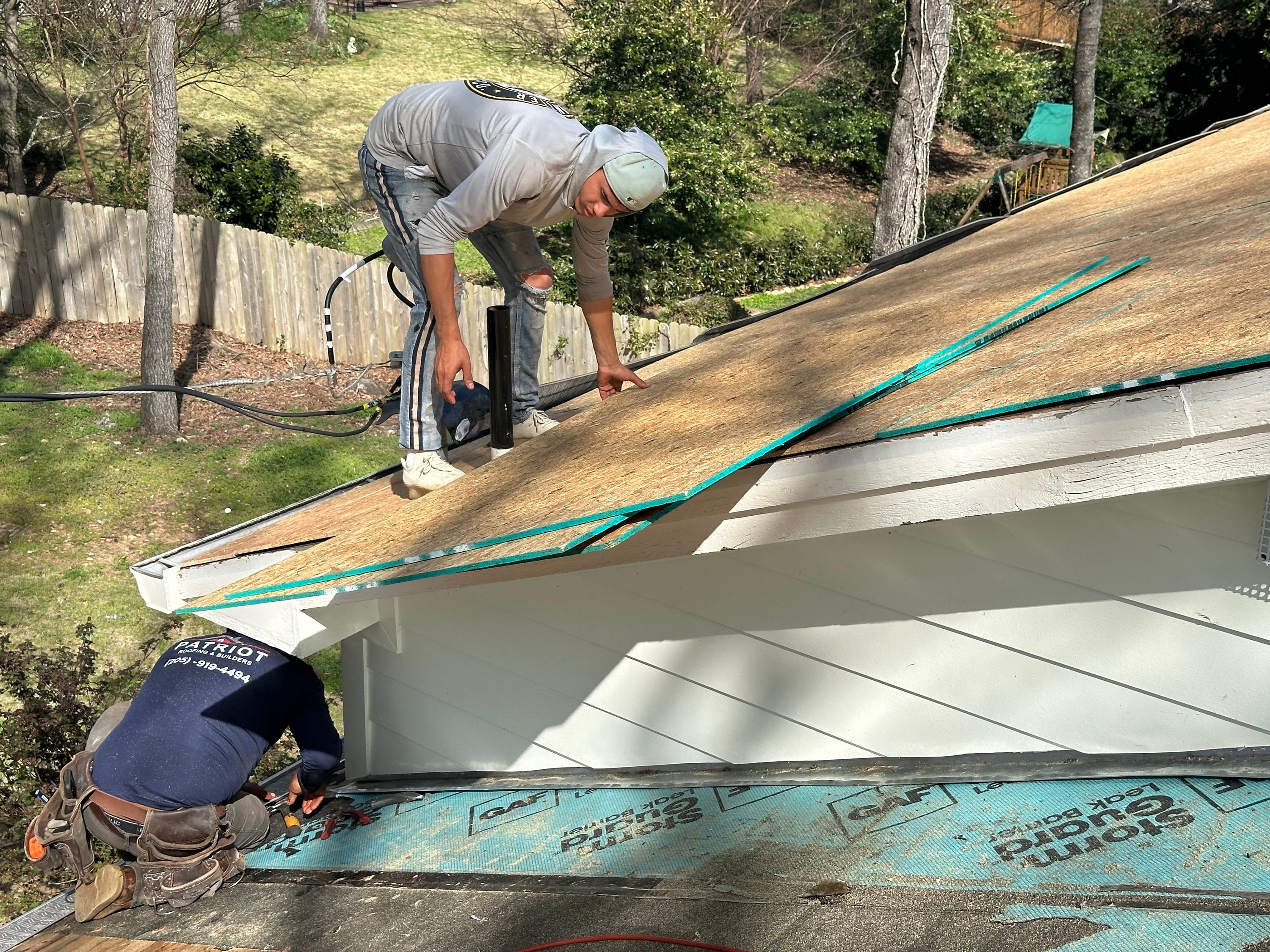 Roofers installing plywood decking and leak barrier during a roof replacement in Mountain Brook's Brookwood Forest.