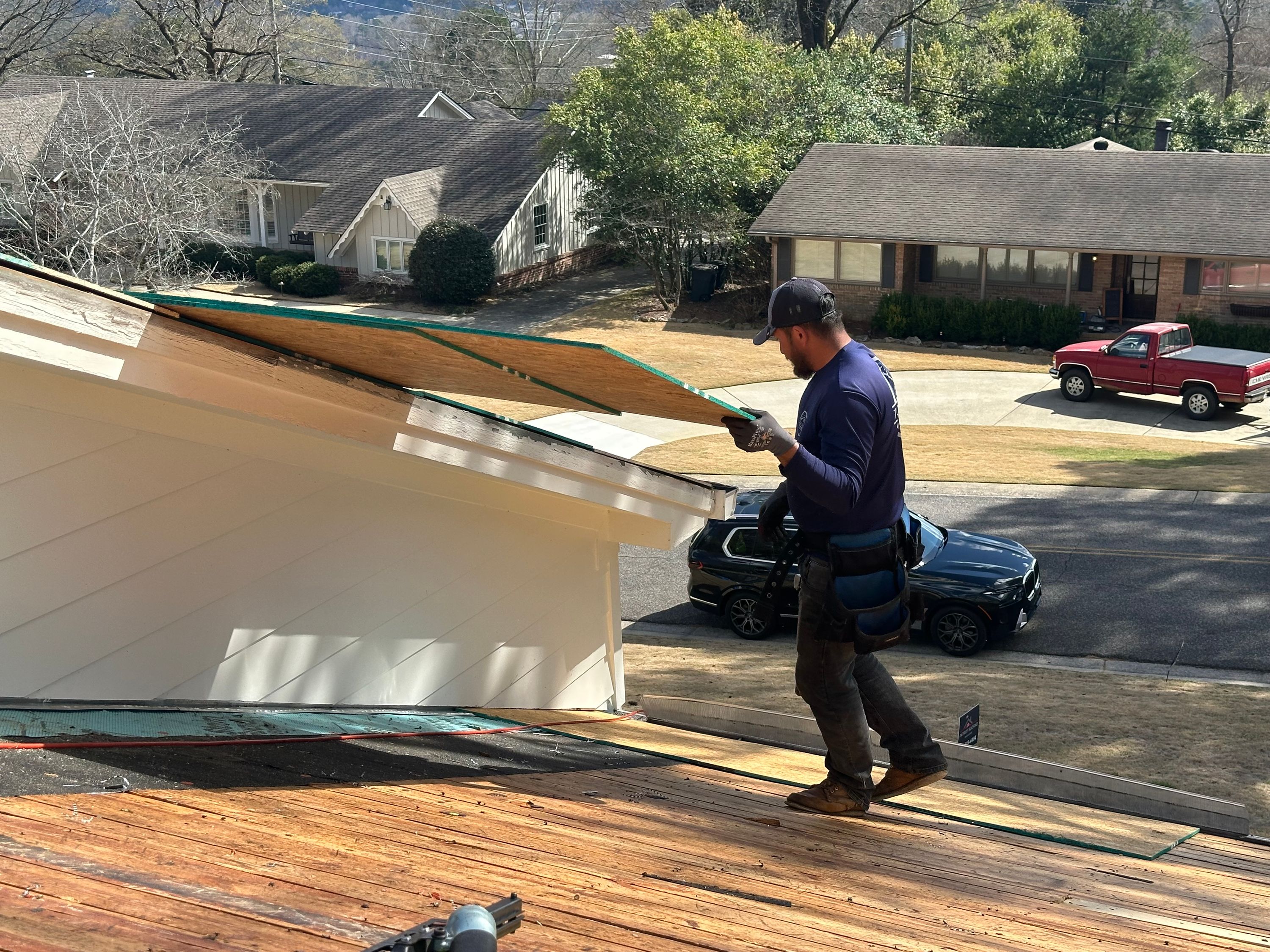 Roofer installing new plywood decking during a roof replacement in Mountain Brook's Brookwood Forest neighborhood.