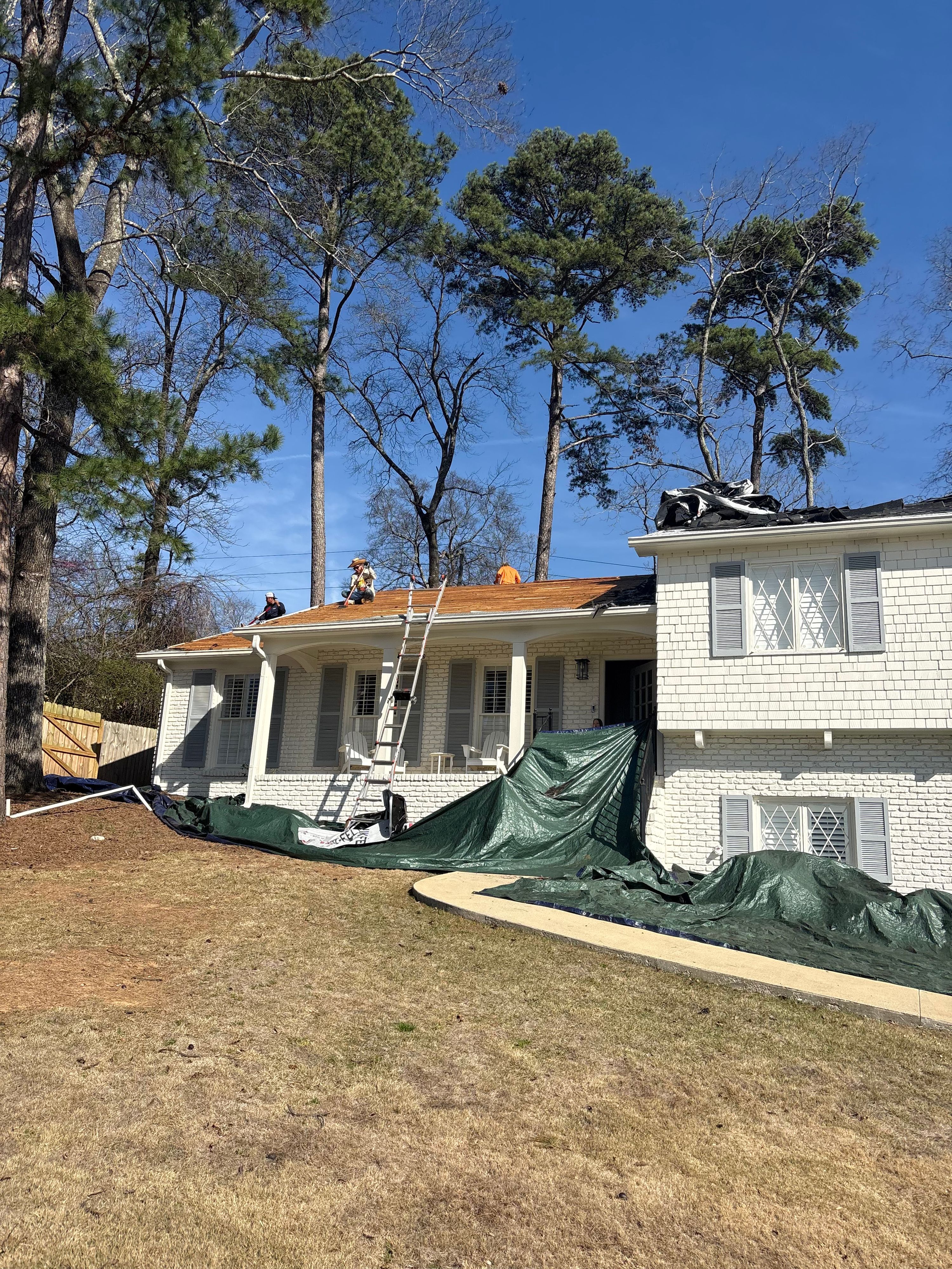 Roof replacement in progress on a white brick home in Mountain Brook's Brookwood Forest neighborhood.