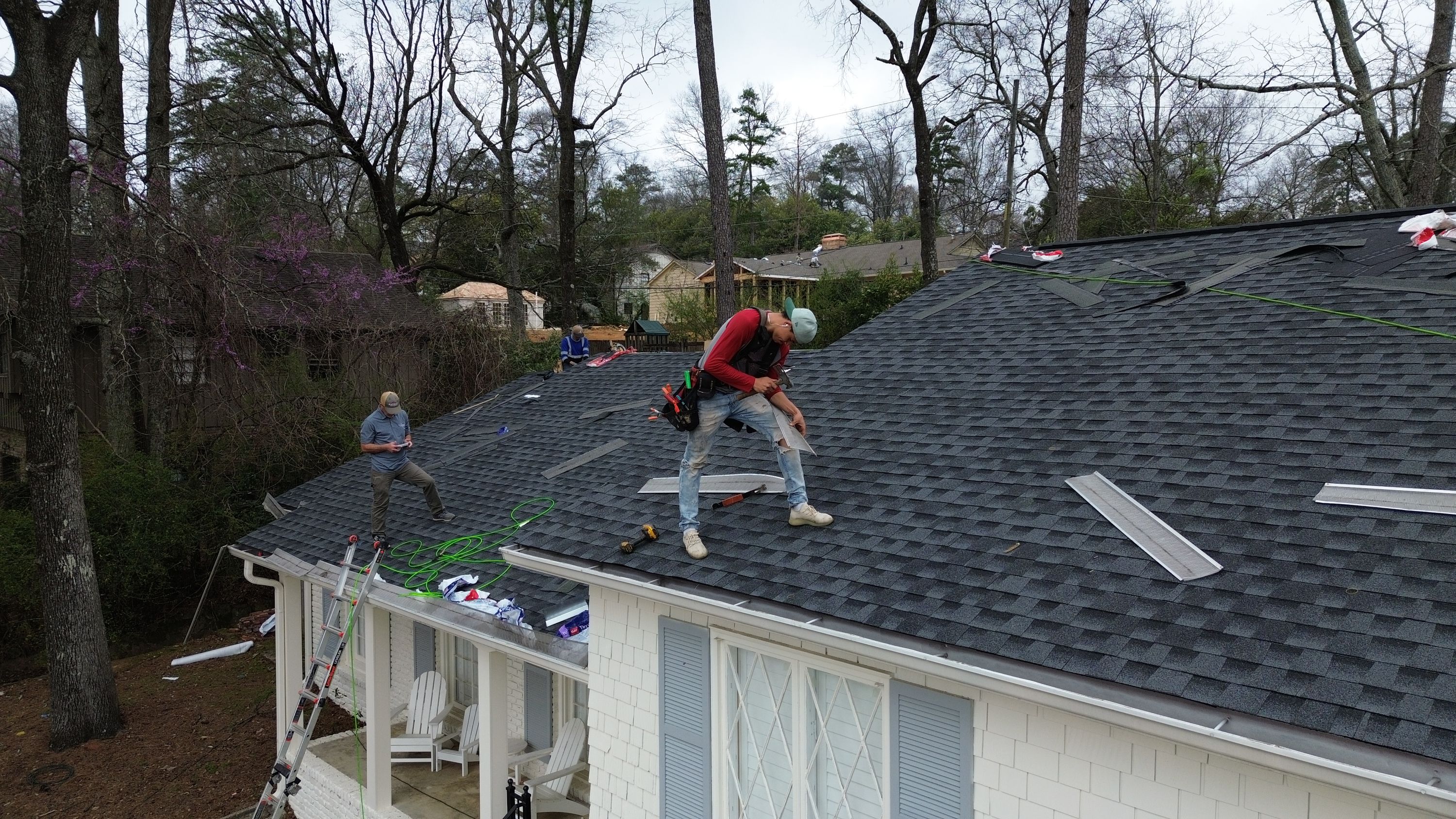 Contractors performing a professional roof replacement on a white home in Mountain Brook's Brookwood Forest.