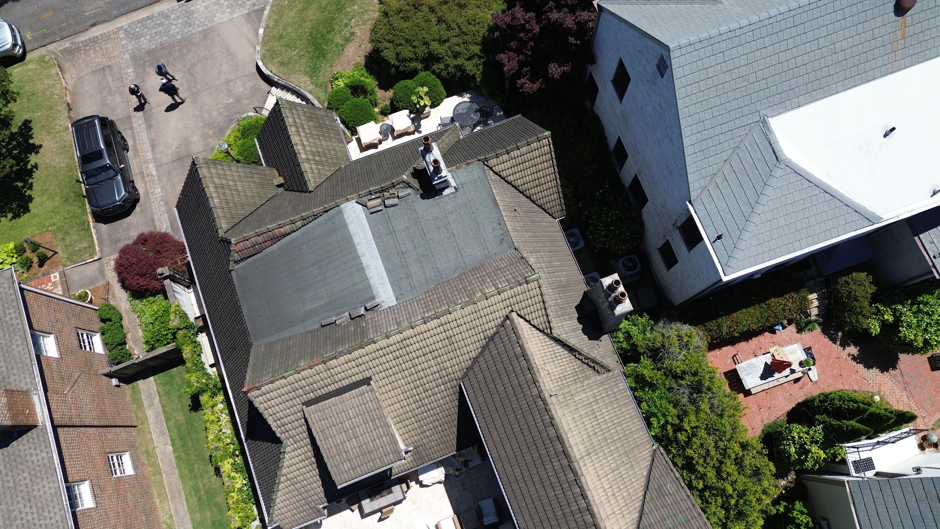 High-angle view shows multiple tile roof planes and a central flat section during roof repair.