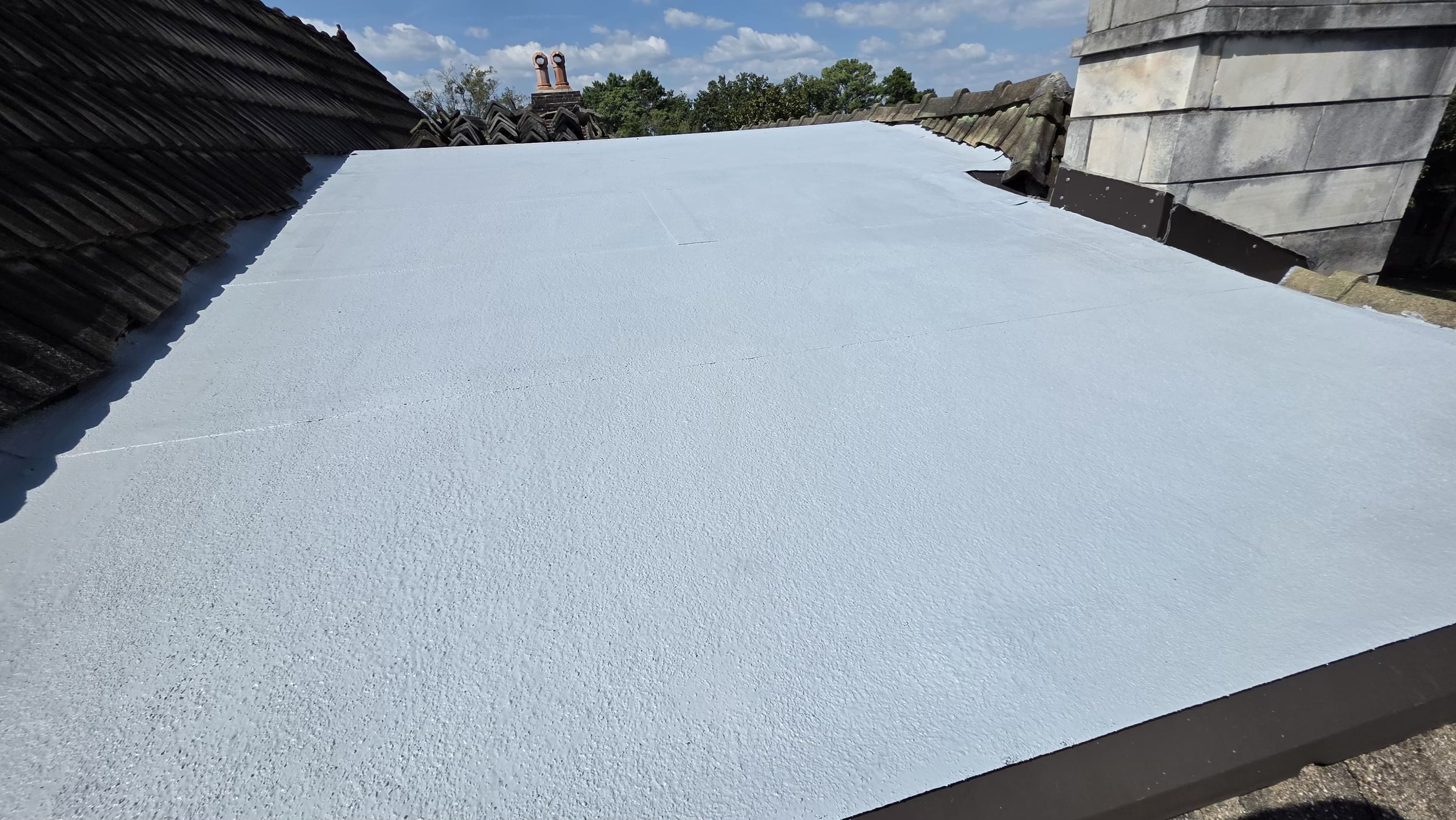 A completed elastomeric coating on a flat roof plane during a roof repair project in Forest Park.