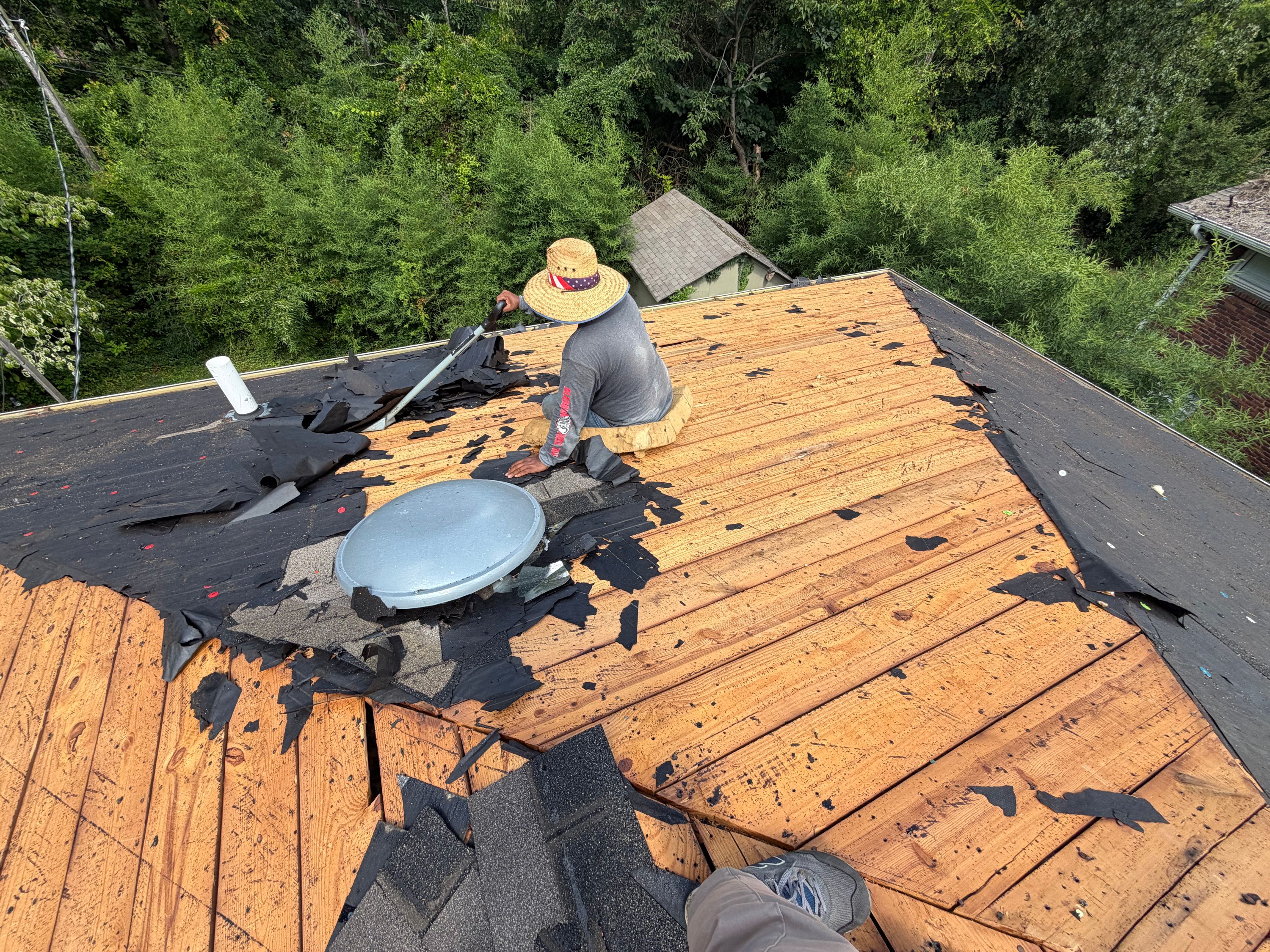 Removing damaged shingles down to the wood plank decking during a Crestwood South roof replacement.