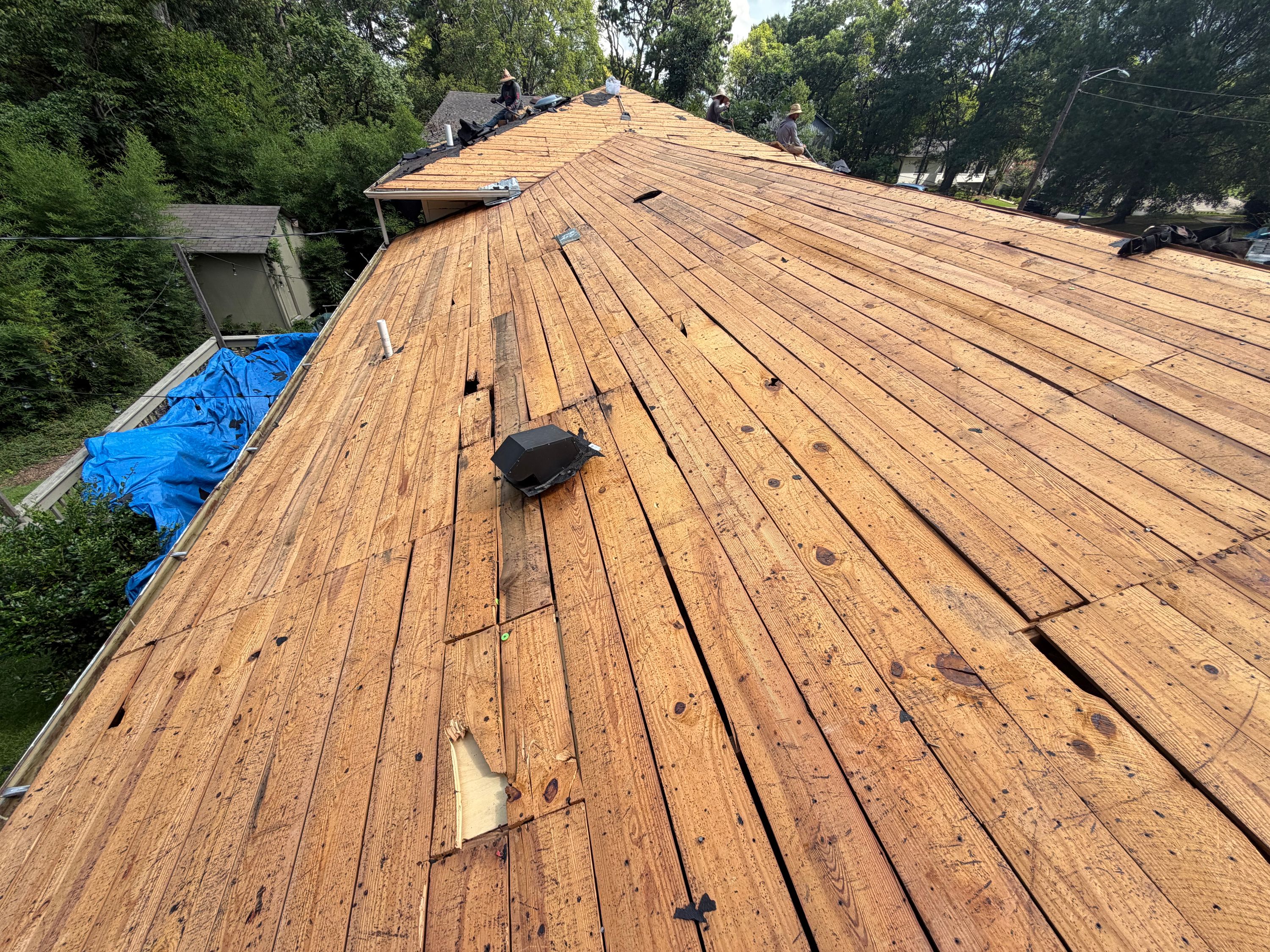 Exposed wood decking planks await new shingles on a residential roof replacement project in Birmingham.