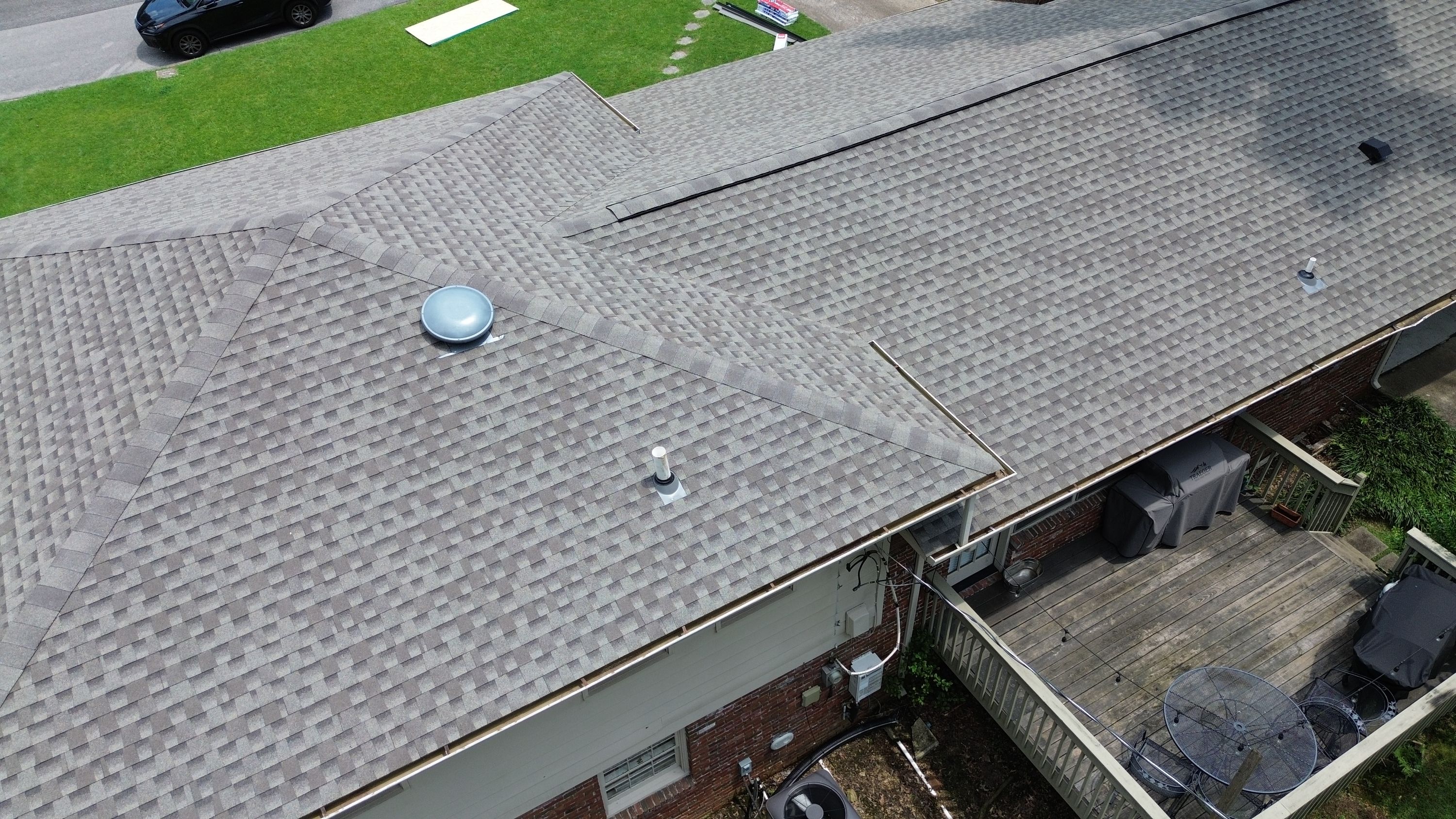Close-up of a new plumbing pipe boot seal installed alongside fresh asphalt shingles near the gutter line.