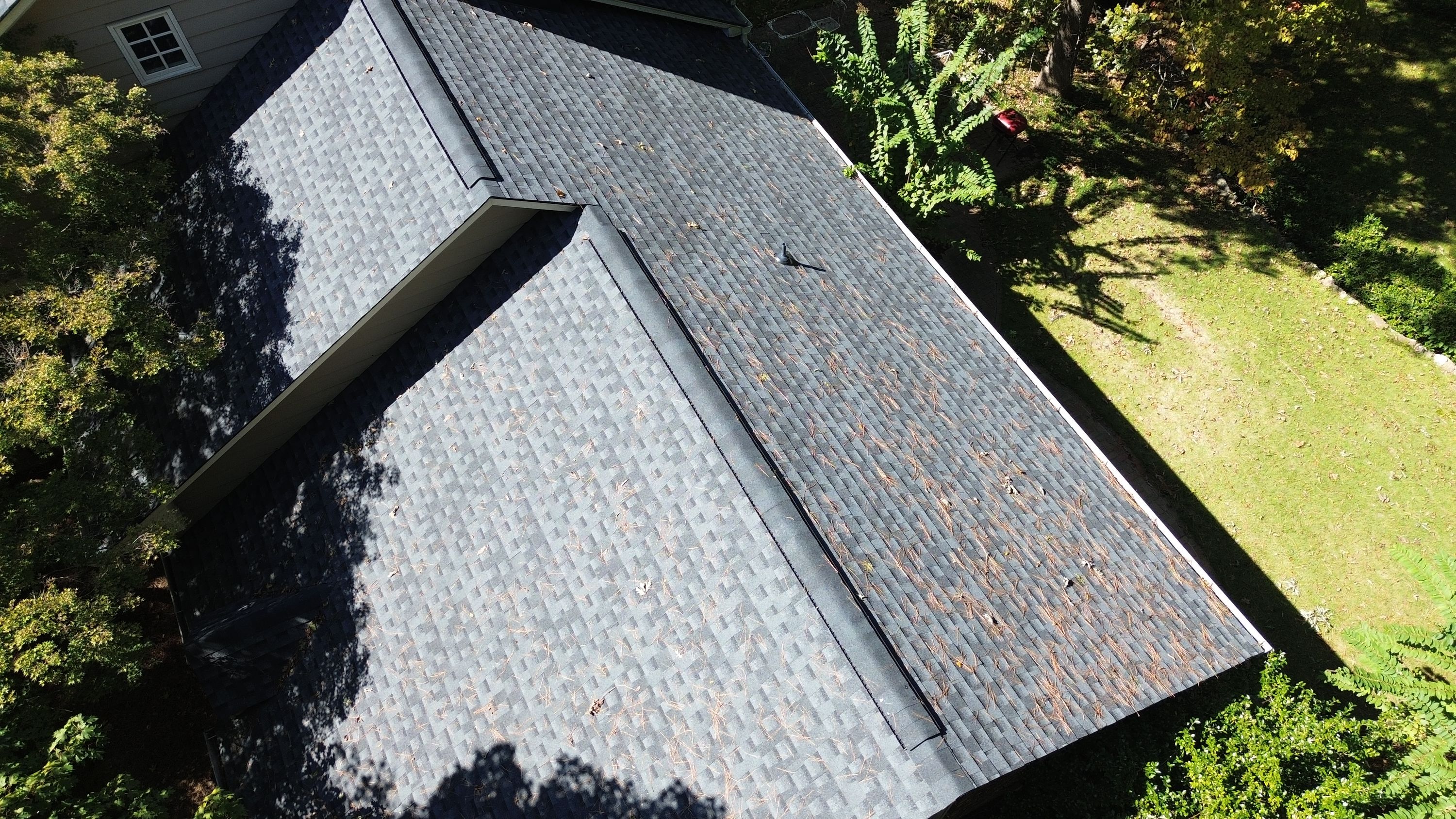Close-up view of a shingle roof valley and ridge vent following a roof replacement.