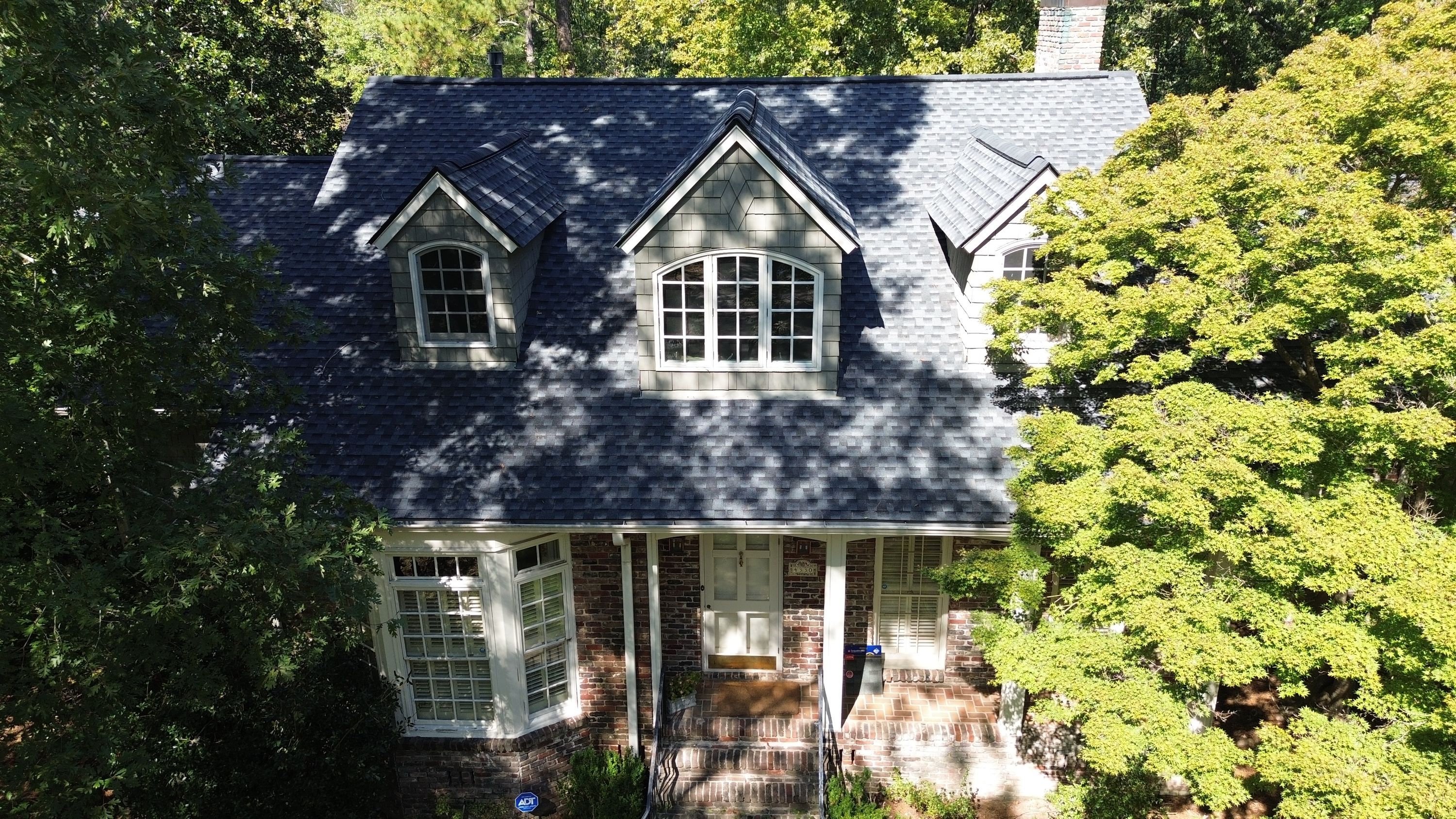 Elevated view of a completed shingle roof replacement over a brick home front entryway in Cherokee Bend.