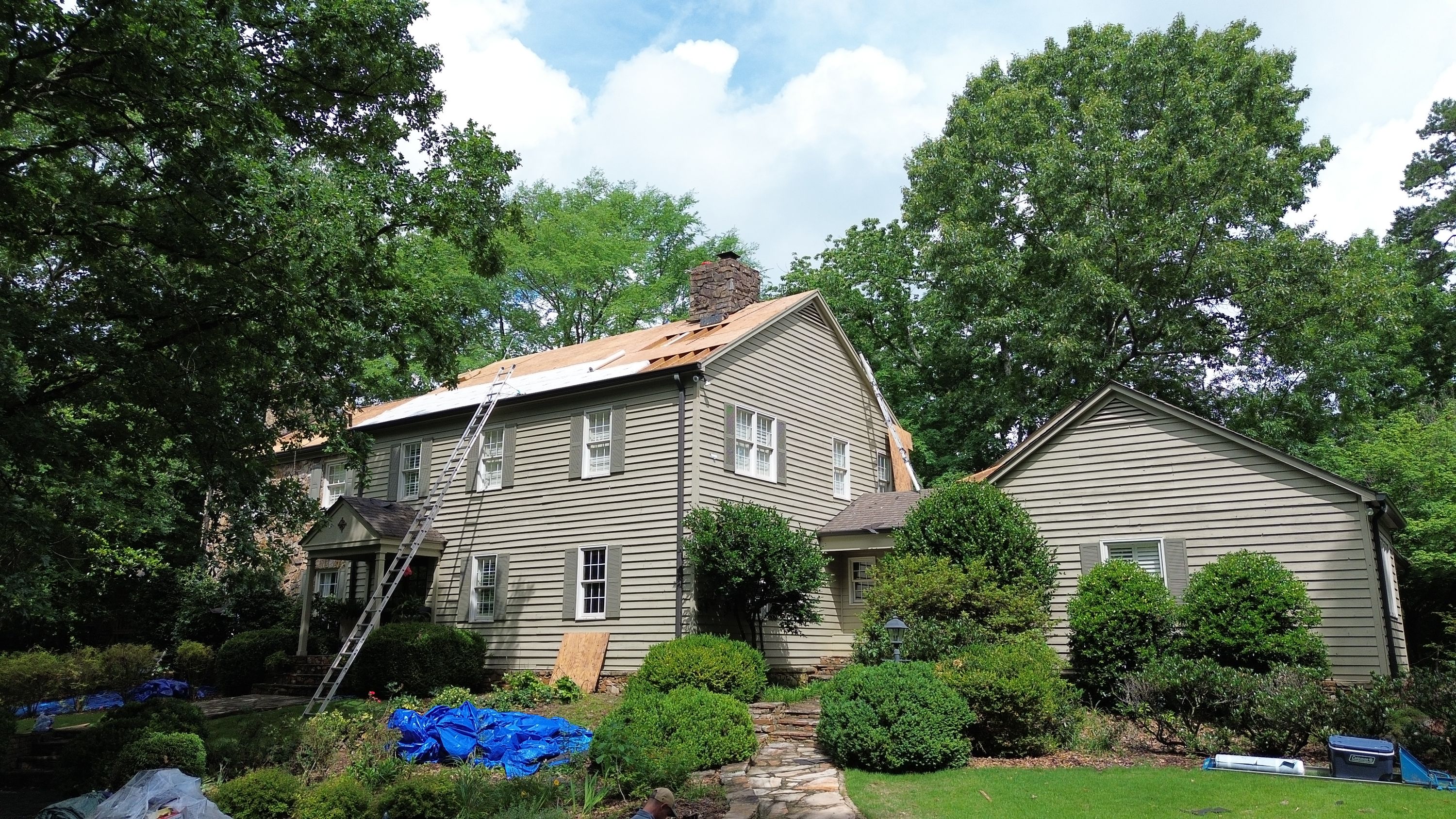 Roof replacement in progress on a Mountain Brook home along Old Leeds Road, showing exposed wood decking.
