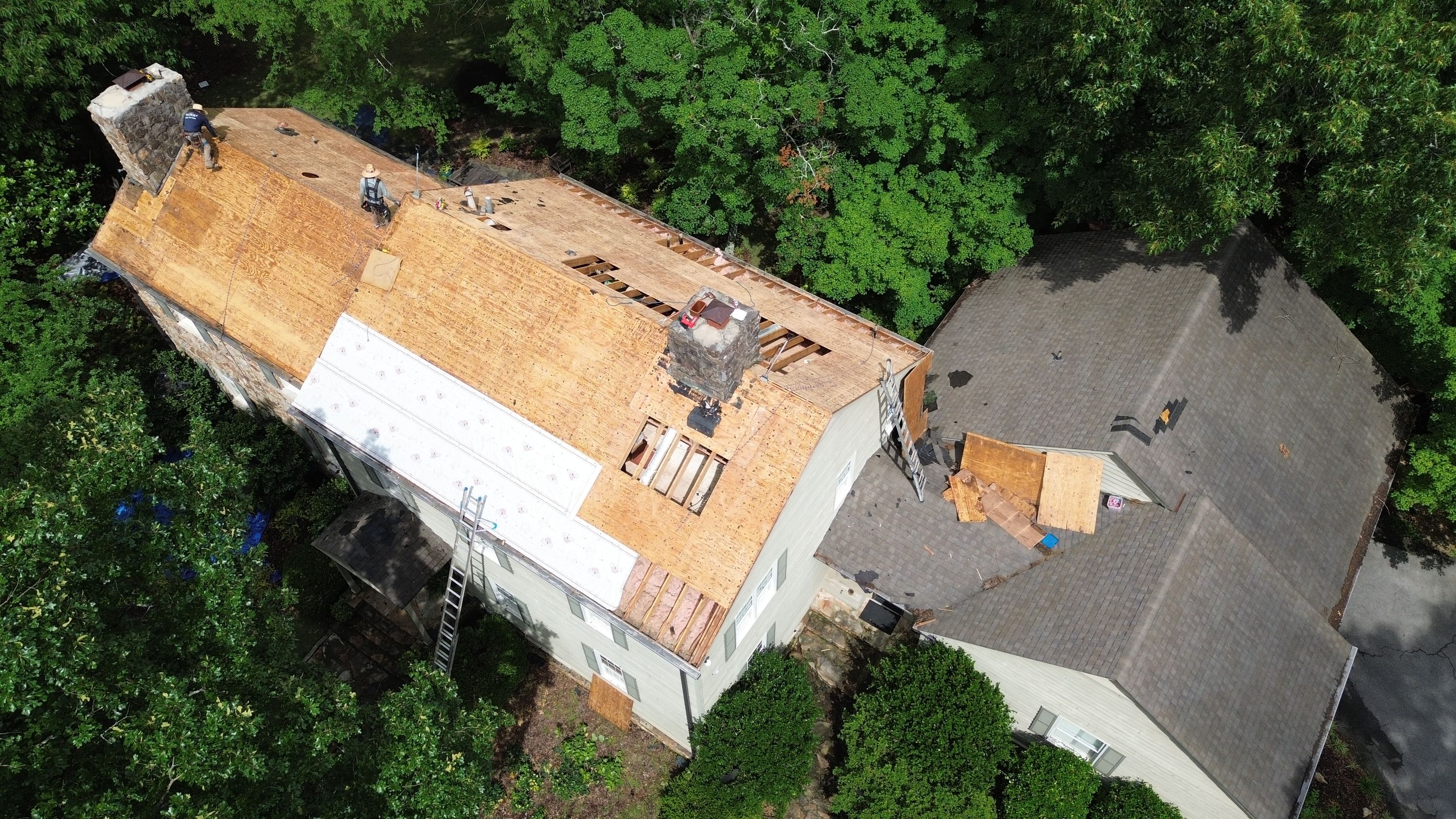 Roof replacement in progress on a home in Mountain Brook with exposed plywood decking.