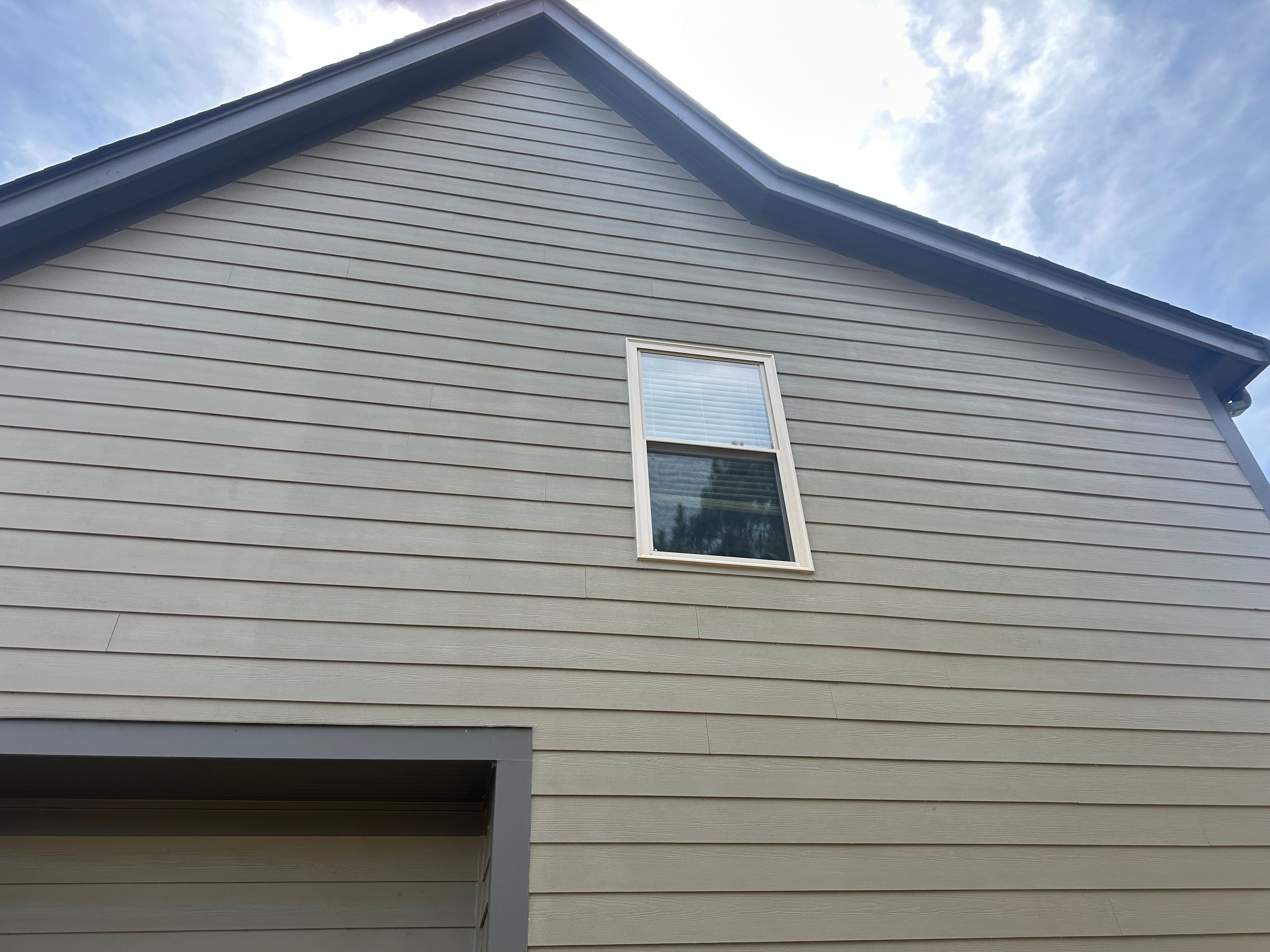 Completed window replacement and roof repair on a home with light horizontal siding in Chelsea Park.