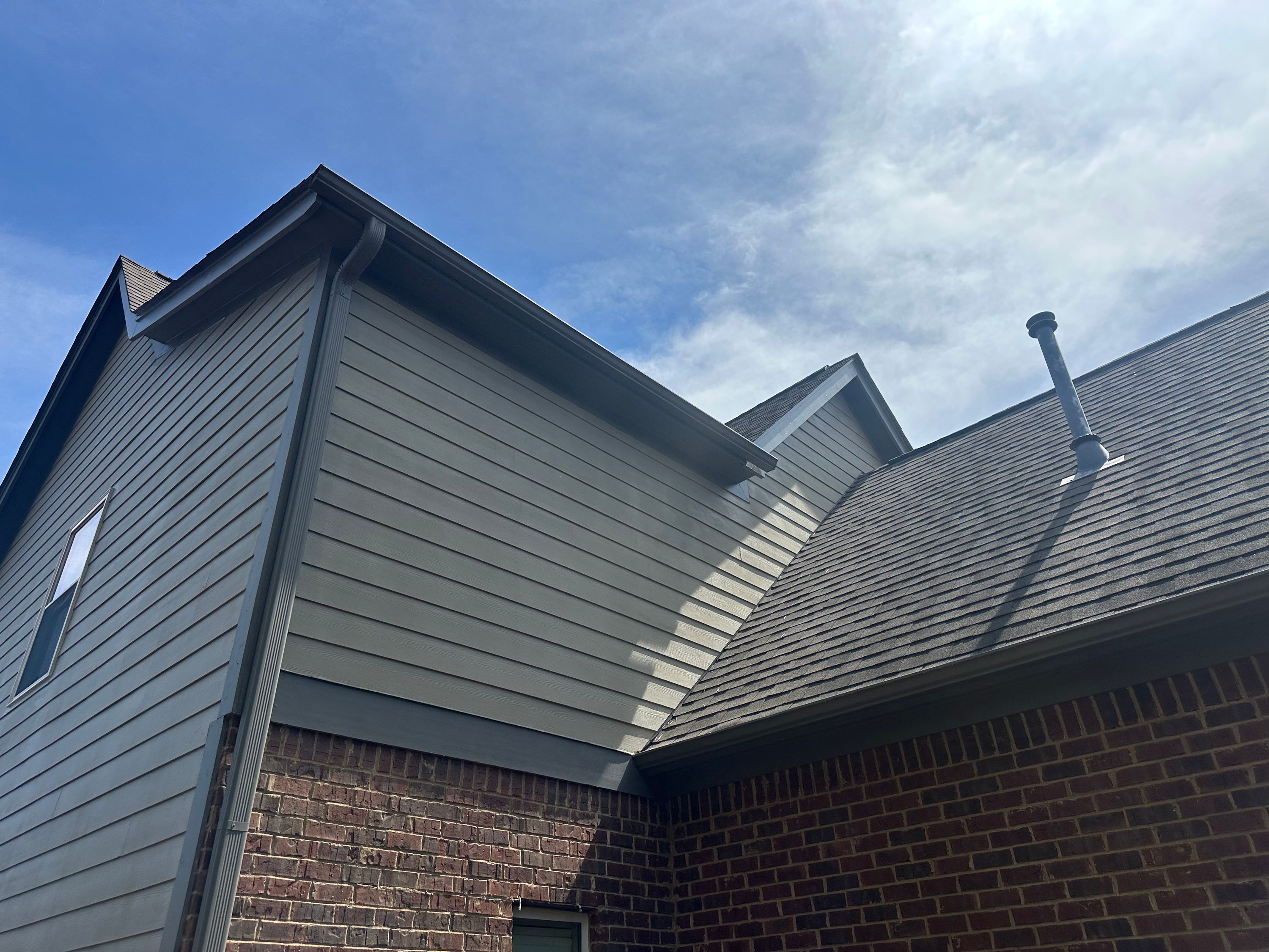 Completed roof repair and window replacement on a brick and siding house in Chelsea Park.