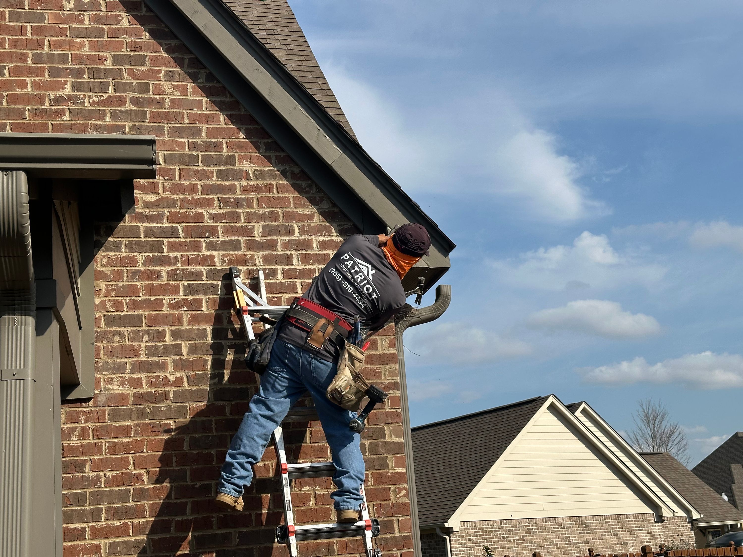 Roofing contractor performing expert roof repair on a brick home in Chelsea Park.