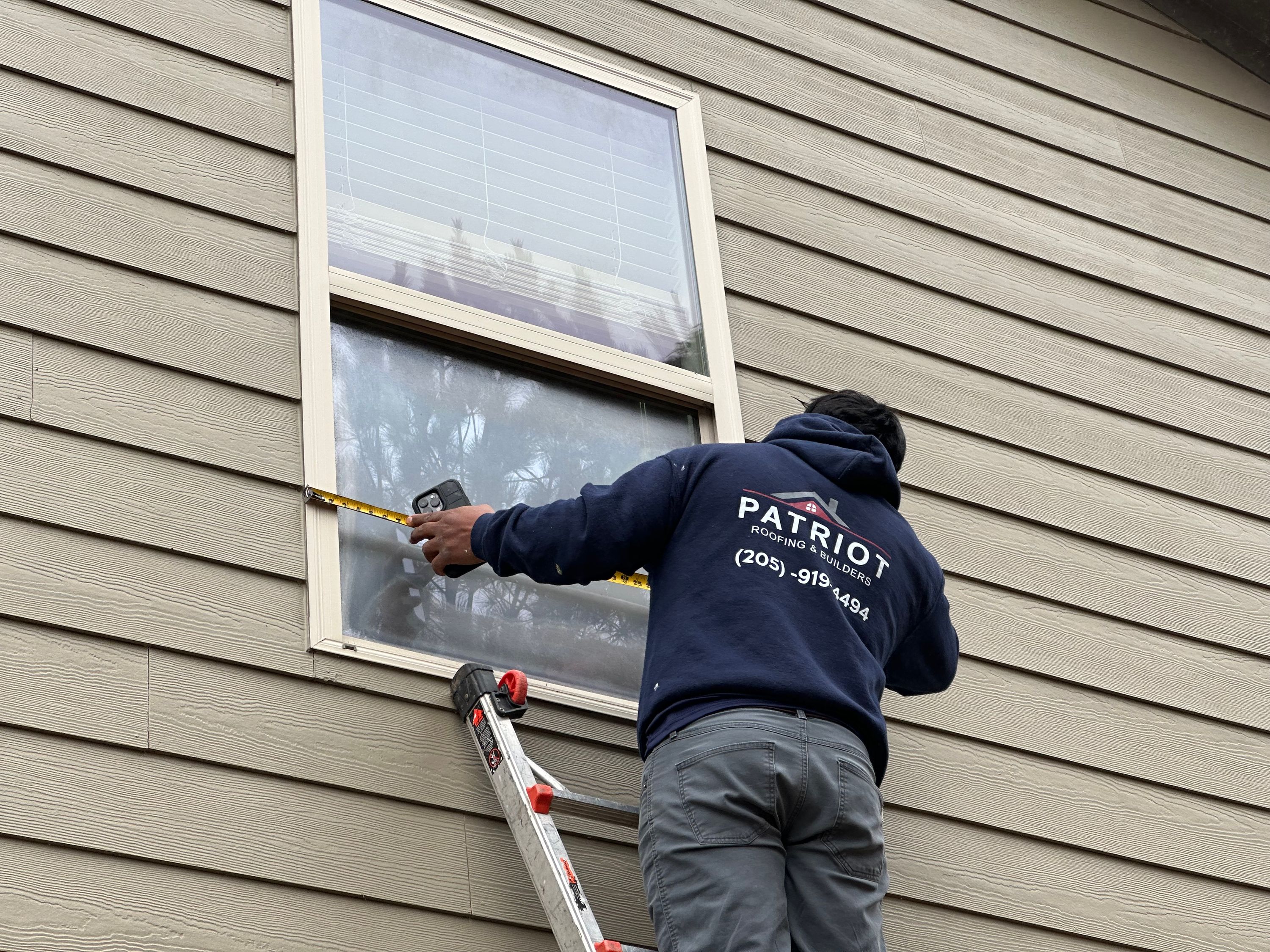 Professional measuring an exterior window for replacement on a home in Chelsea Park.