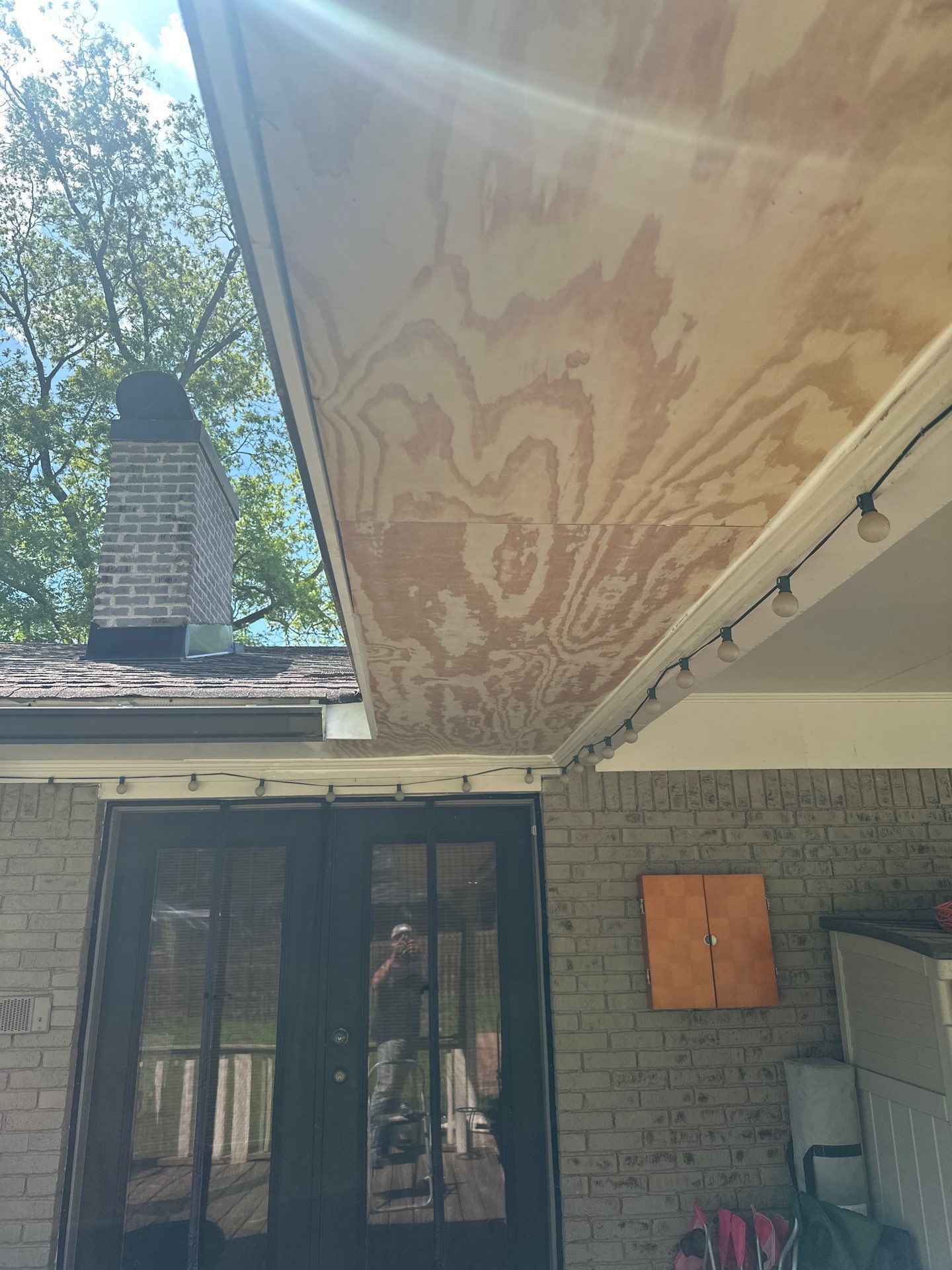 Fresh plywood soffit panels are installed under a porch overhang as part of a roof repair in Historic Irondale.