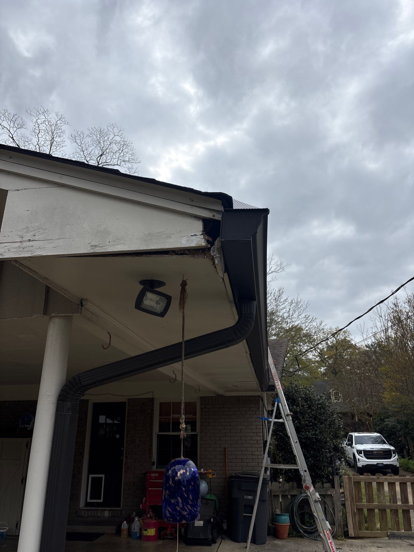Damaged fascia wood is exposed near a gutter corner before a roof repair is completed.