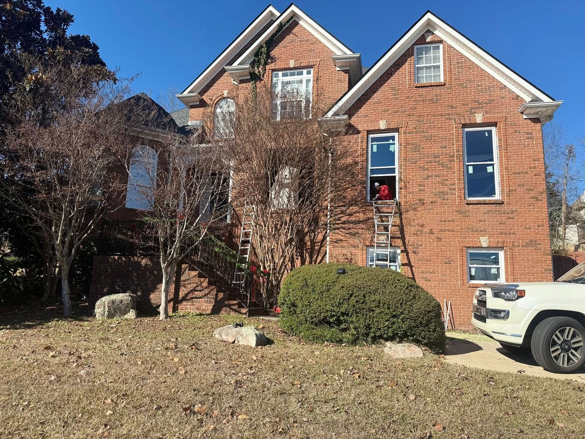 Patriot Roofing & Builders team performing a professional window installation on a large brick house in Hoover.