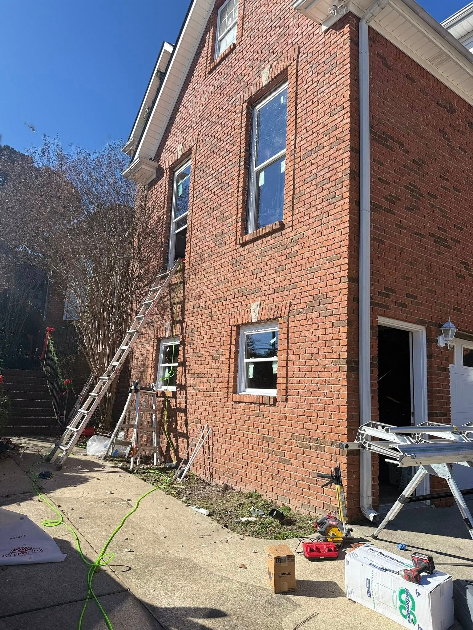 Side view of a window replacement project in Hoover, Alabama featuring ladders and professional equipment.