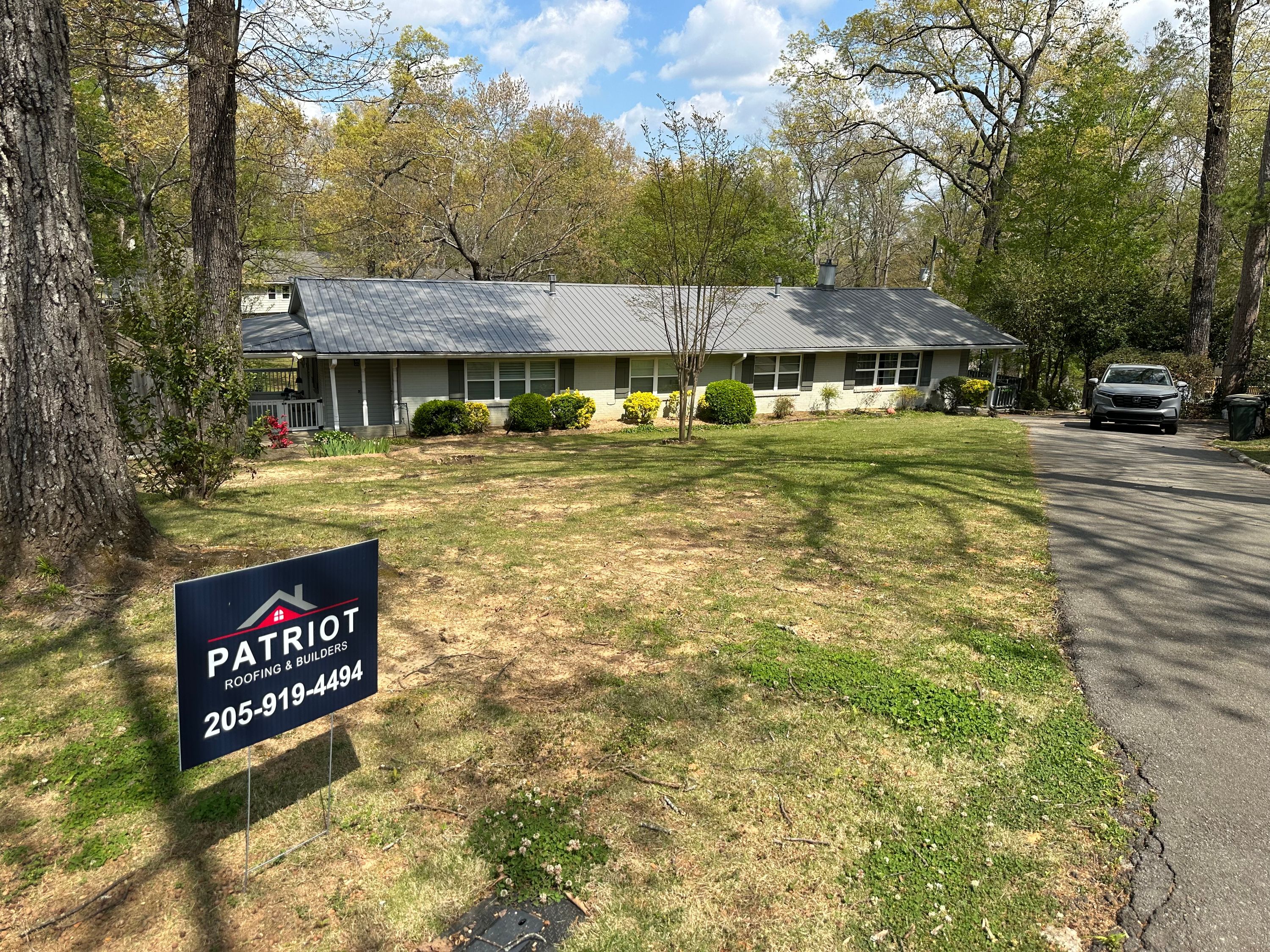 Gray metal roof replacement on a home in Vestavia Hills with a Patriot Roofing yard sign in the foreground.