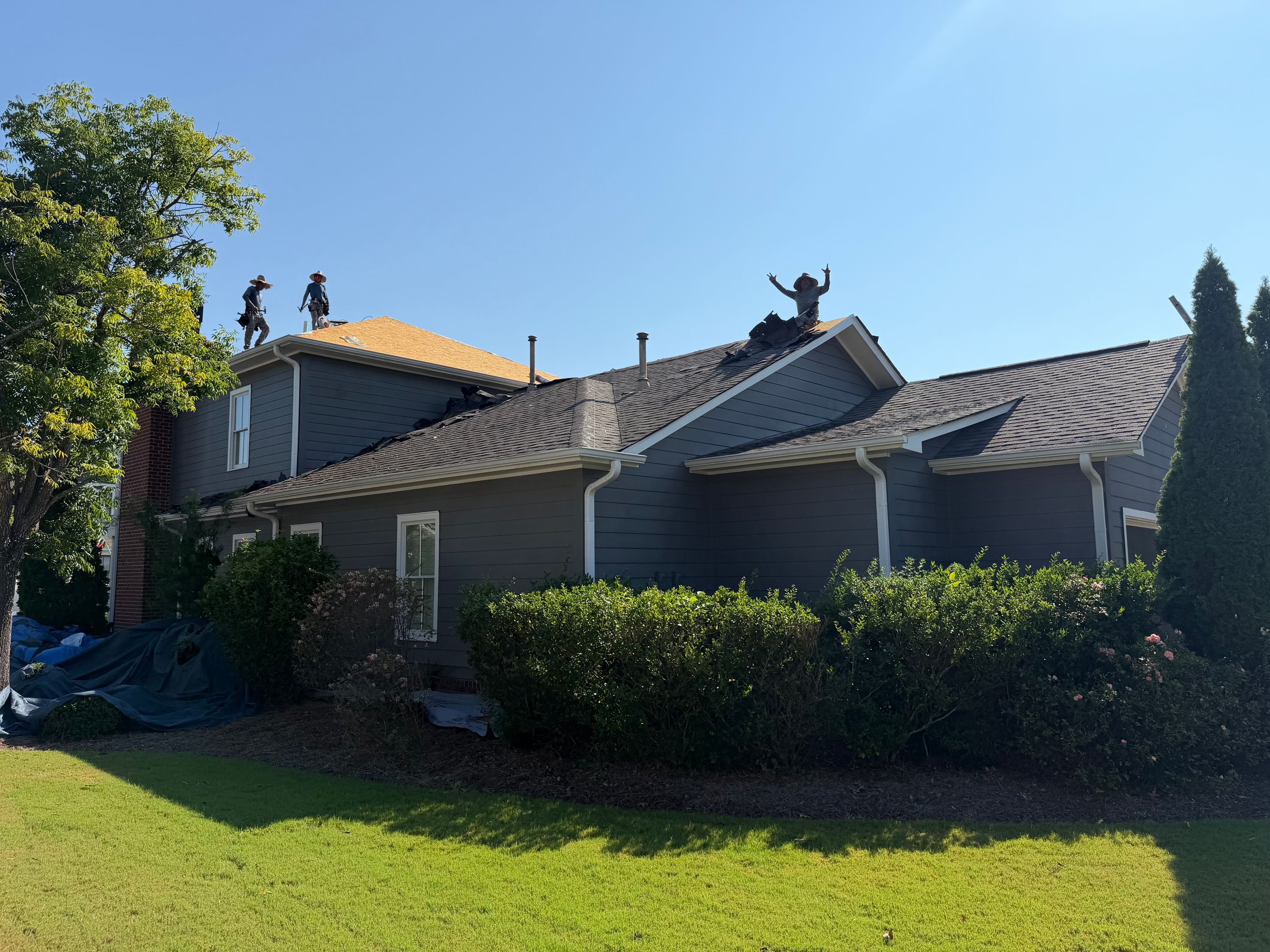 Old grey shingles and vent pipes are visible above the gutters and siding of this home before roof replacement.