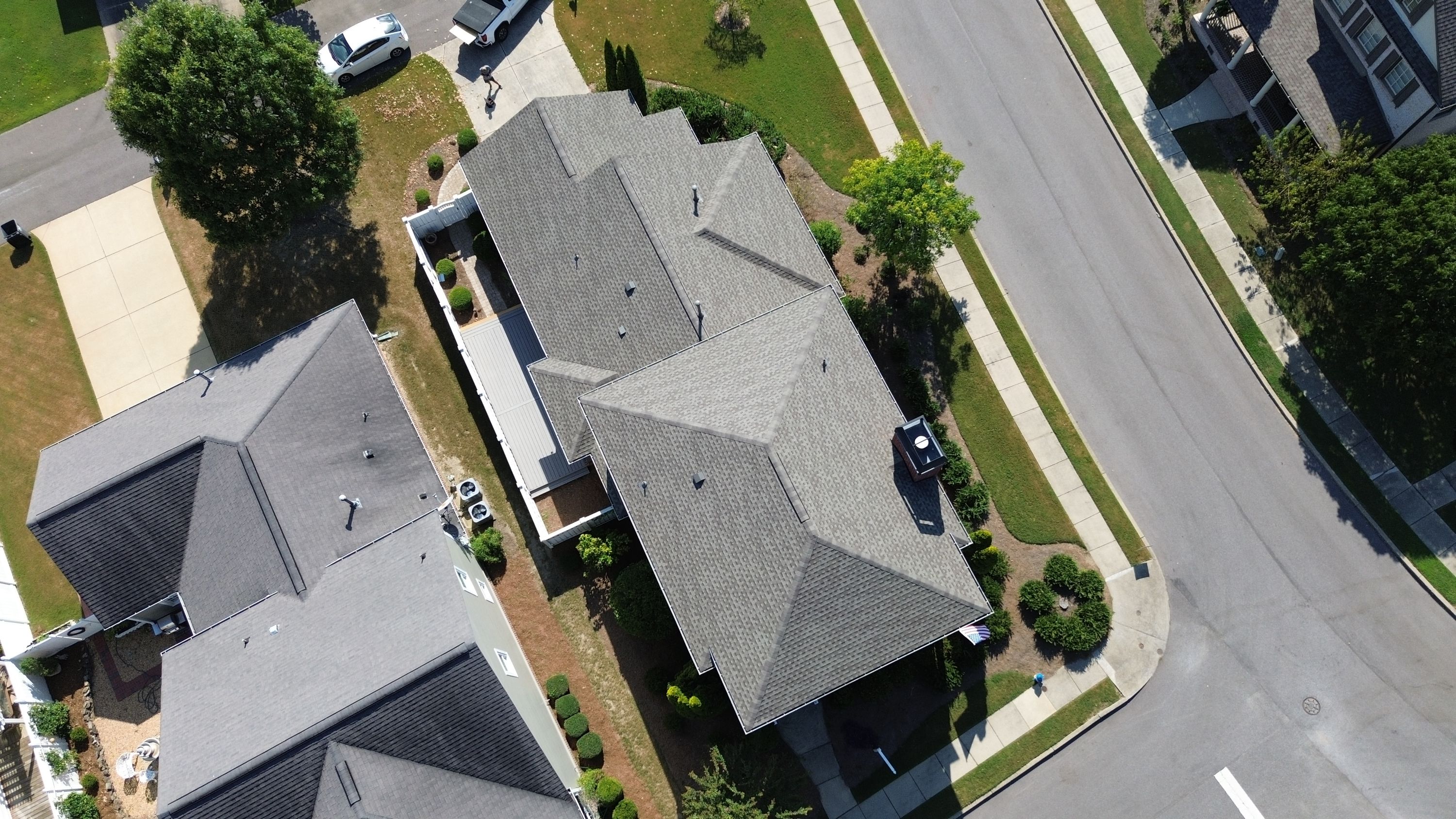 Completed architectural shingle roof replacement showing crisp valleys and hips from a high-angle drone view.