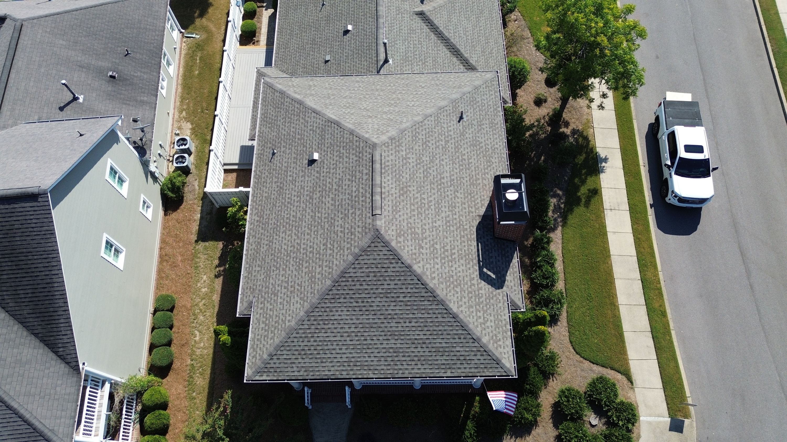 Looking straight down at intersecting valleys and a ridge vent on a newly finished grey shingle roof.