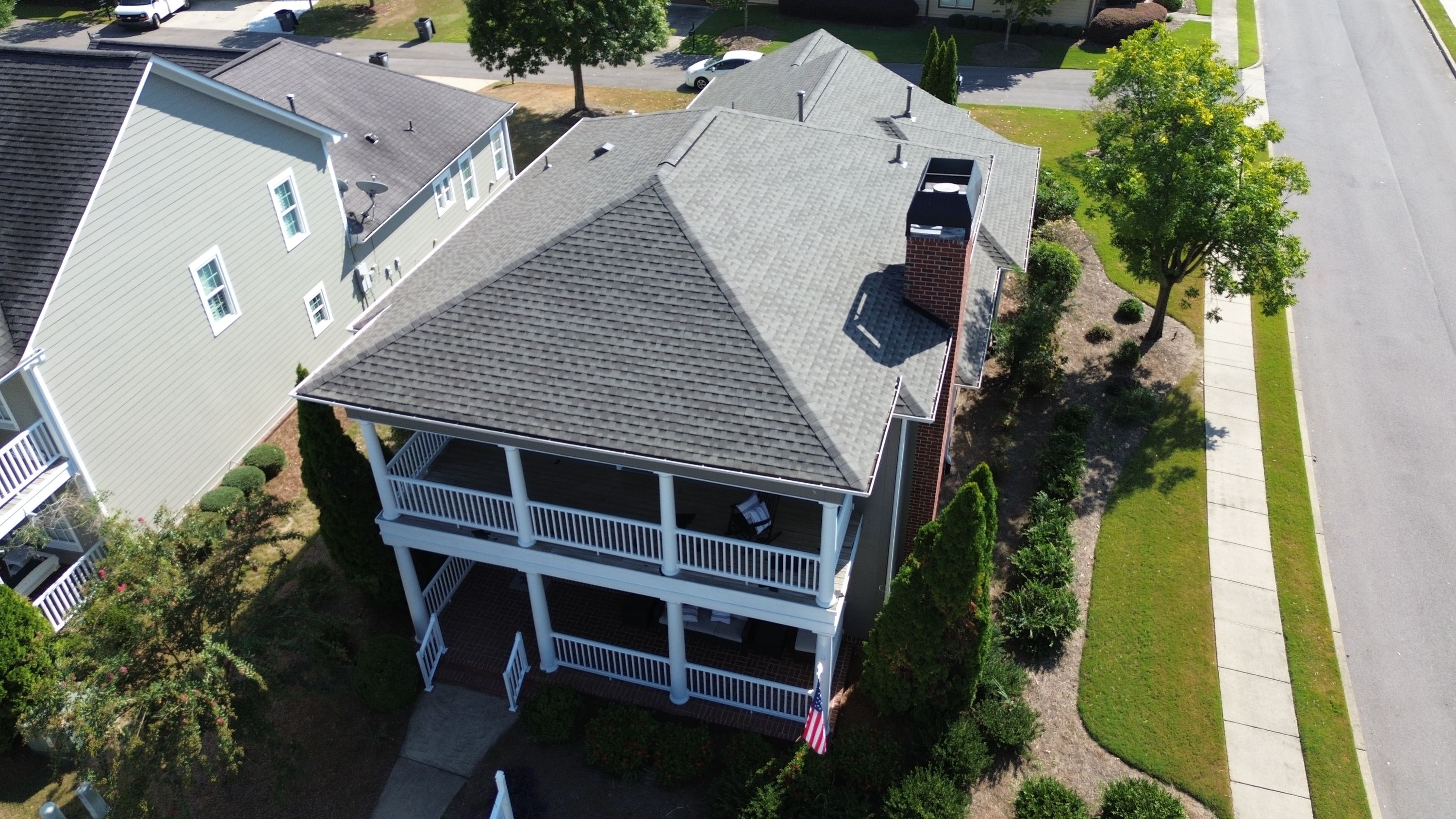 A finished roof replacement sits atop a double-decker white porch in the Beaumont neighborhood.