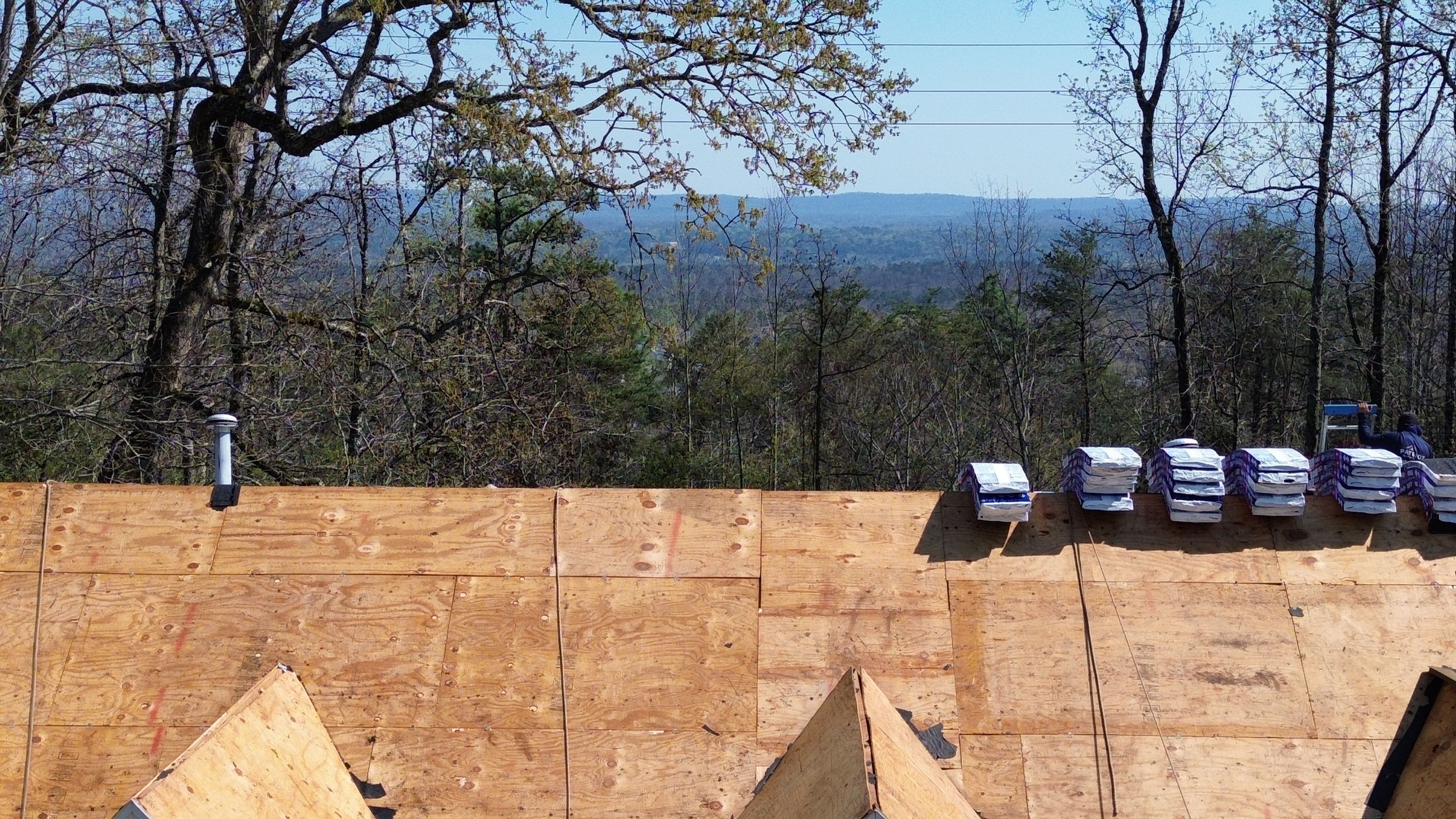 Roof replacement in Hoover's Bluff Park featuring new plywood sheathing and bundles of shingles.