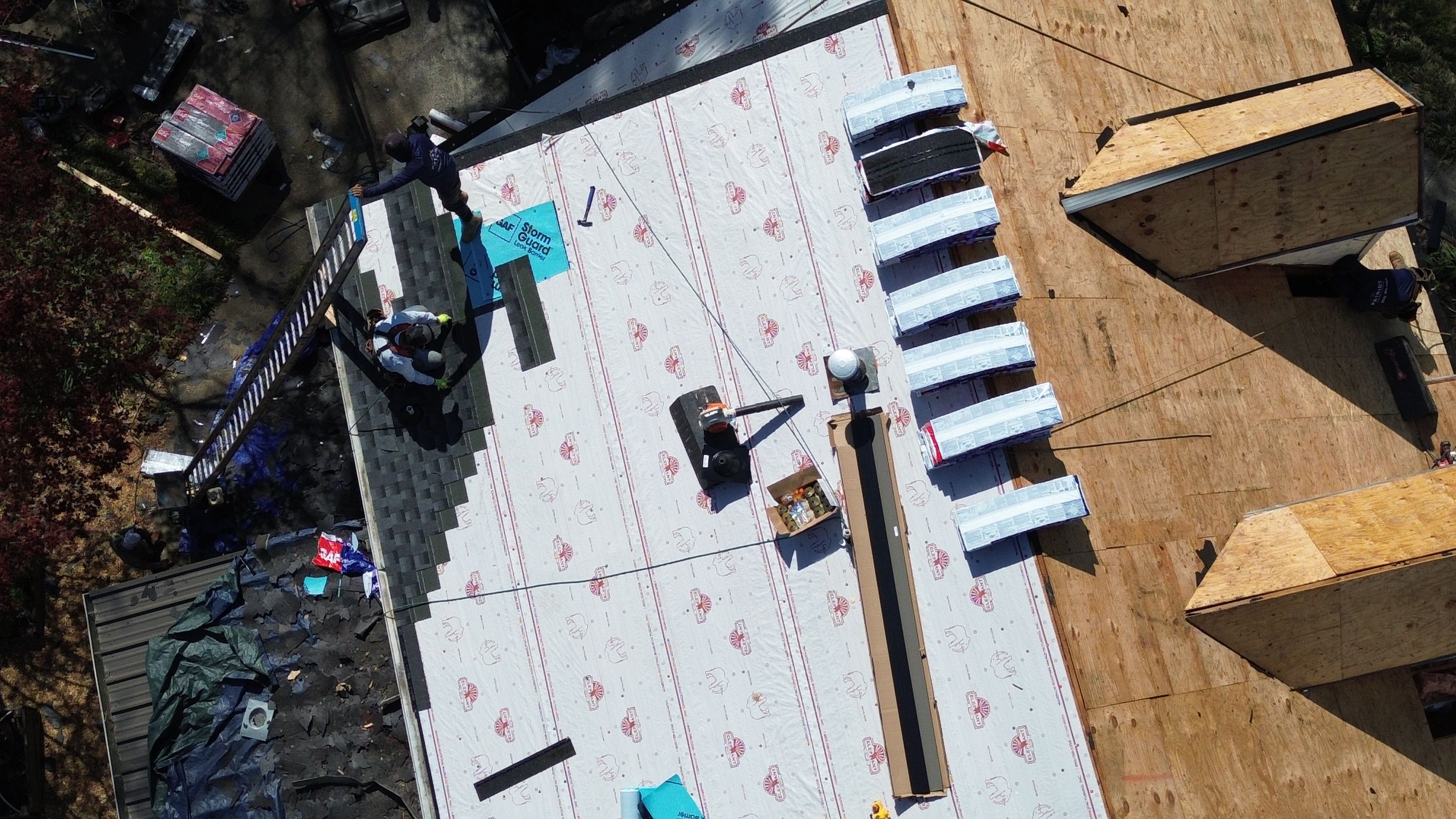 Roofers installing shingles over synthetic underlayment during a roof replacement project in Bluff Park.