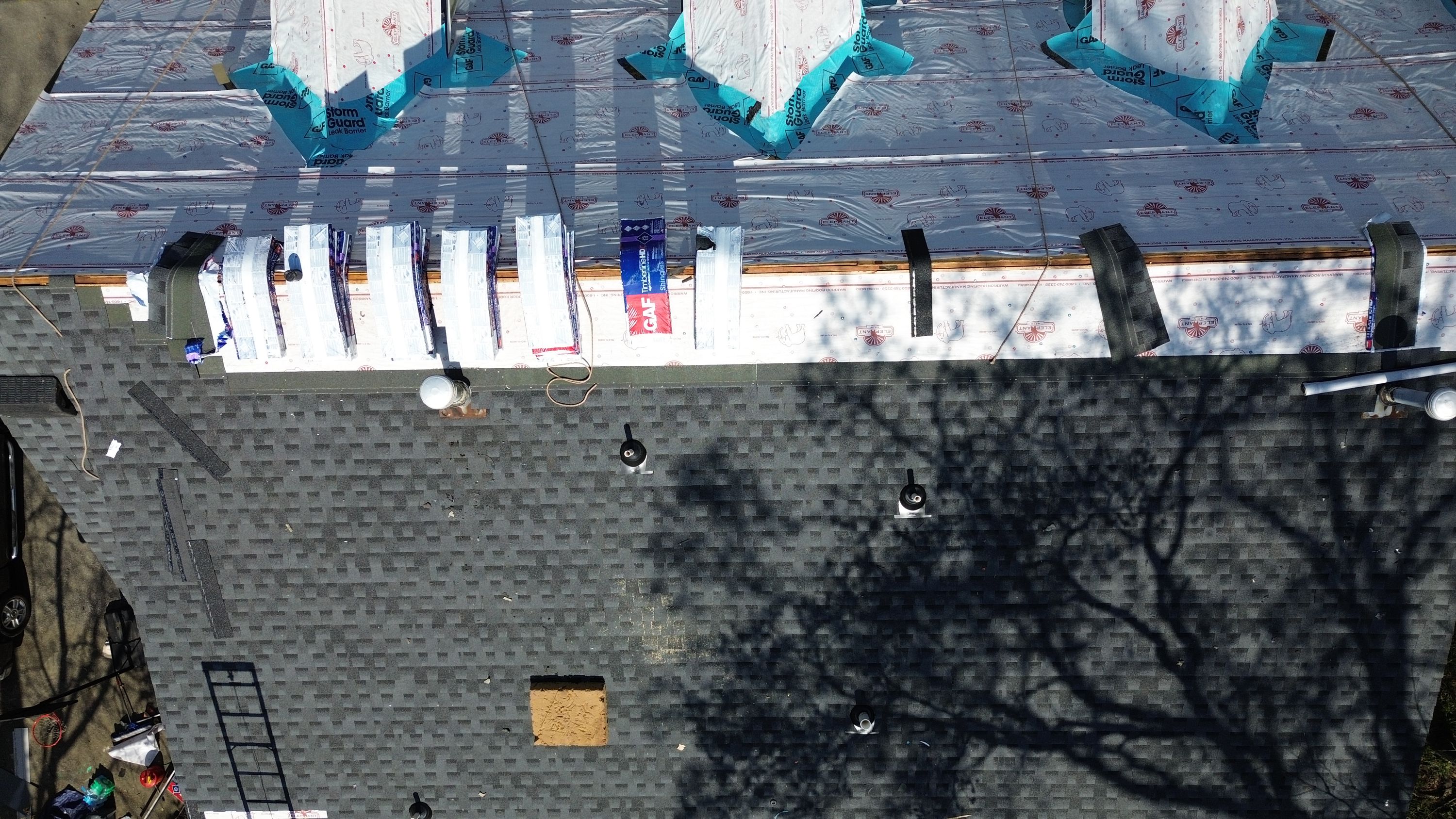 Patriot Roofing and Builders stages GAF shingles over new leak barrier during a Bluff Park roof replacement.