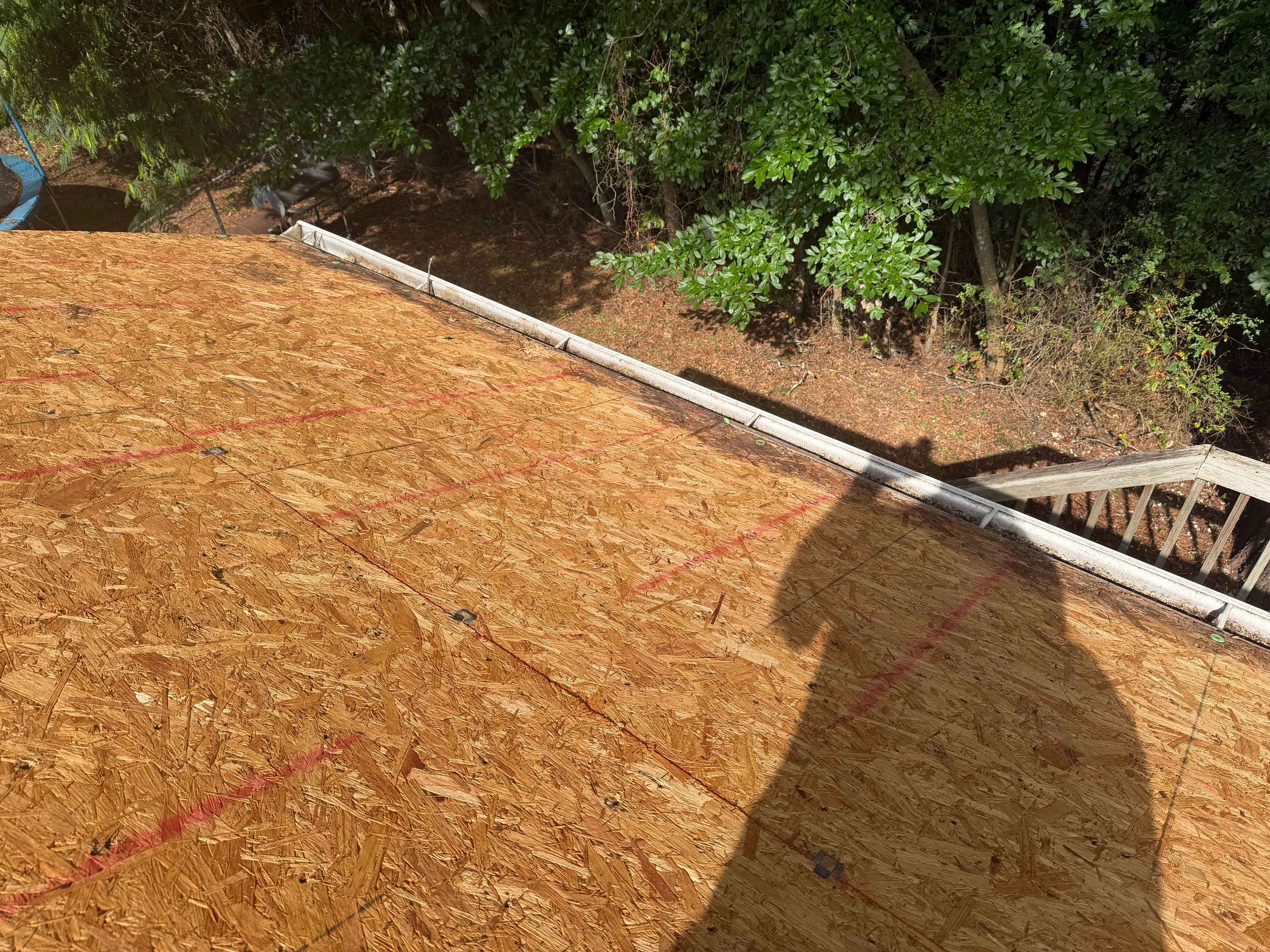 Fresh OSB wood decking meets the gutter line during a roof replacement project in Birmingham.