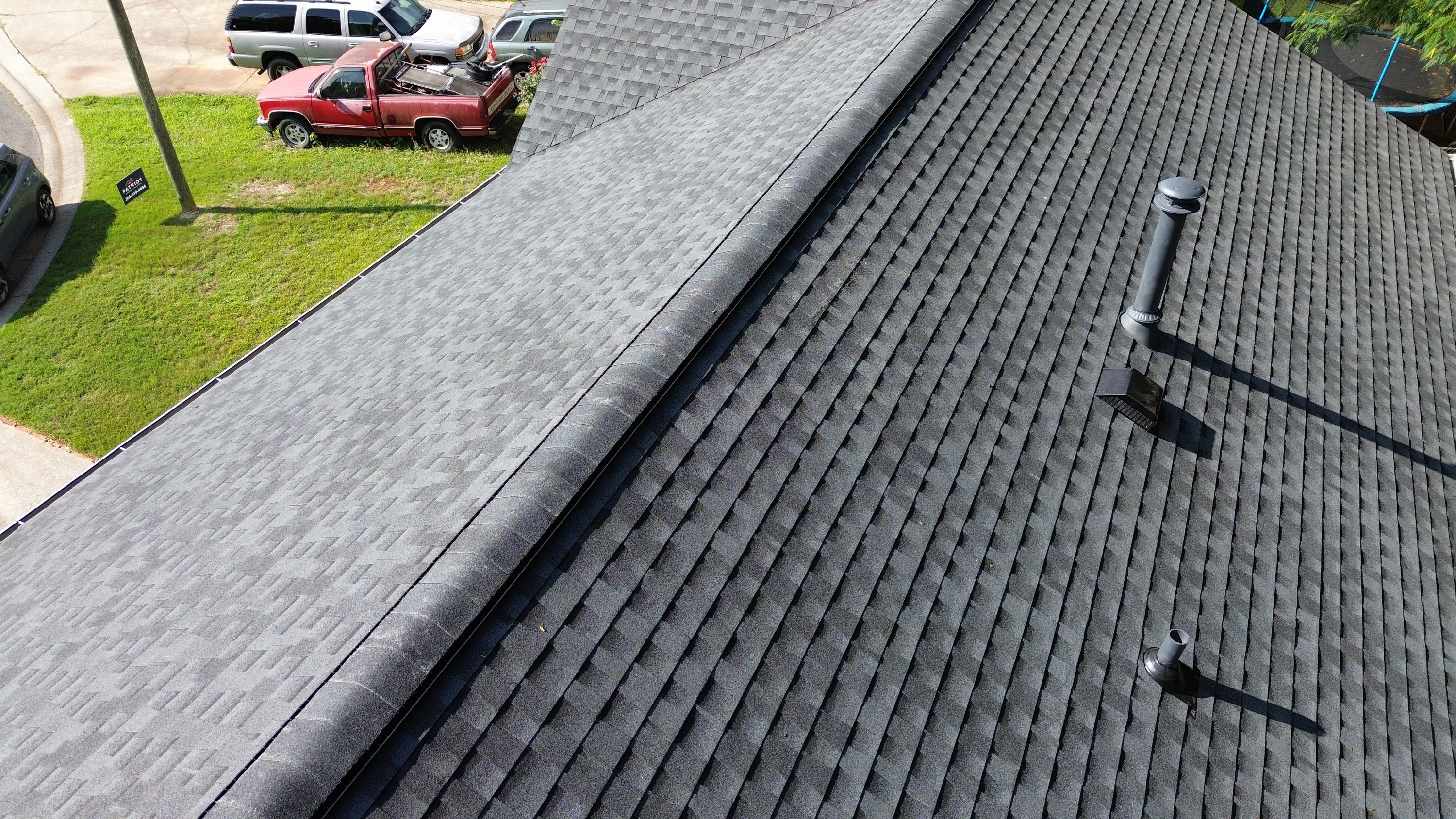 Clean rows of gray asphalt architectural shingles slope downward from a finished ridge.