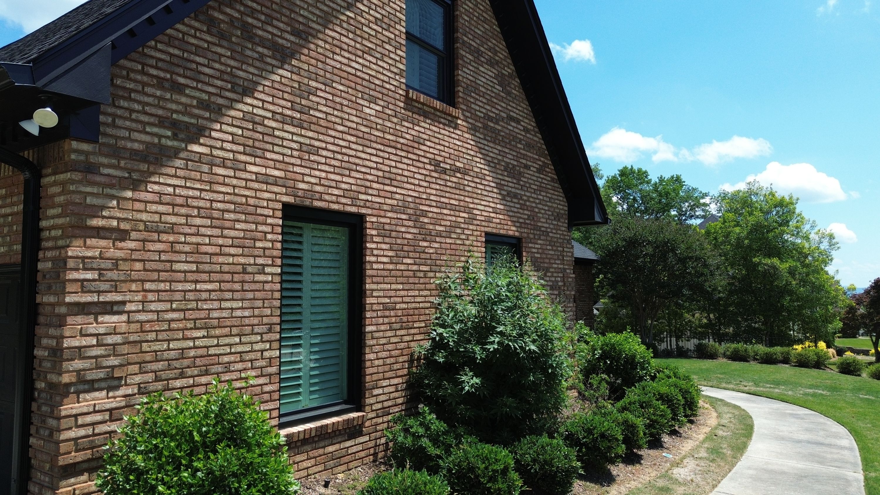 A brick home in Carisbrooke, Hoover featuring dark window replacements and newly installed dark roof shingles.