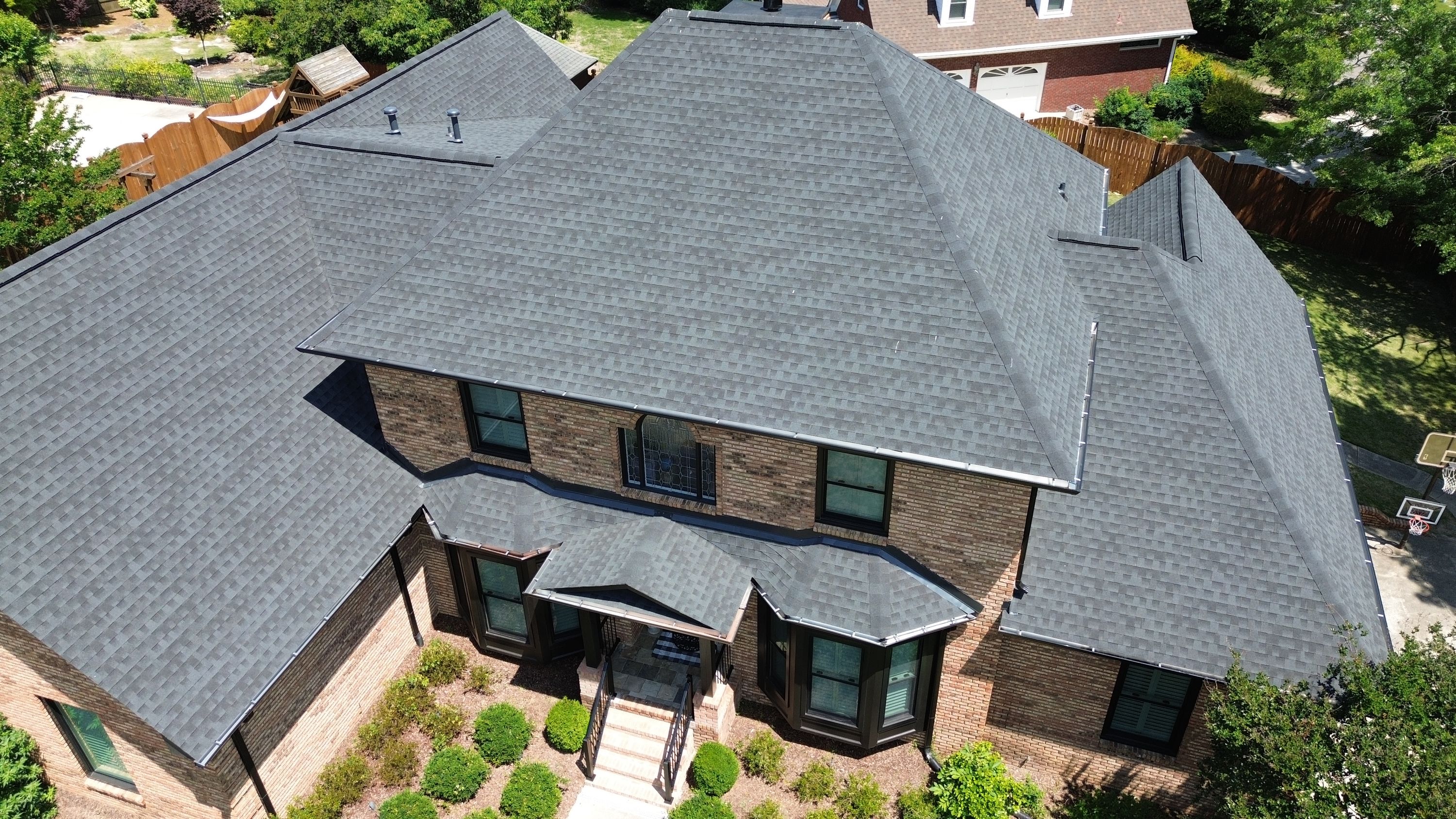 Aerial view of a completed roof replacement featuring dark shingles on a brick home in the Carisbrooke neighborhood.